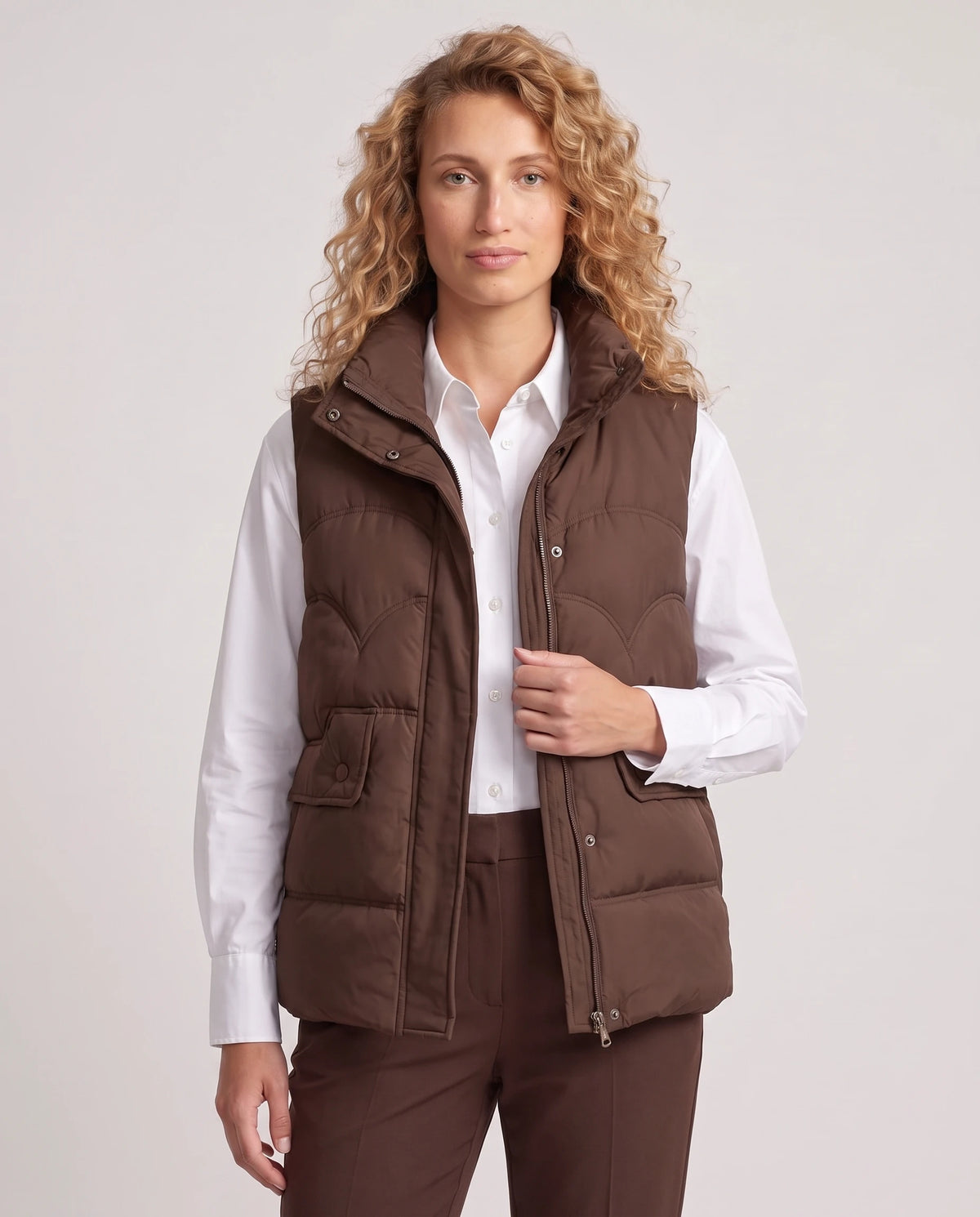Gilet matelassé court à col montant Sylvie en Chocolat Foncé, porté ouvert sur une chemise blanche, plan rapproché