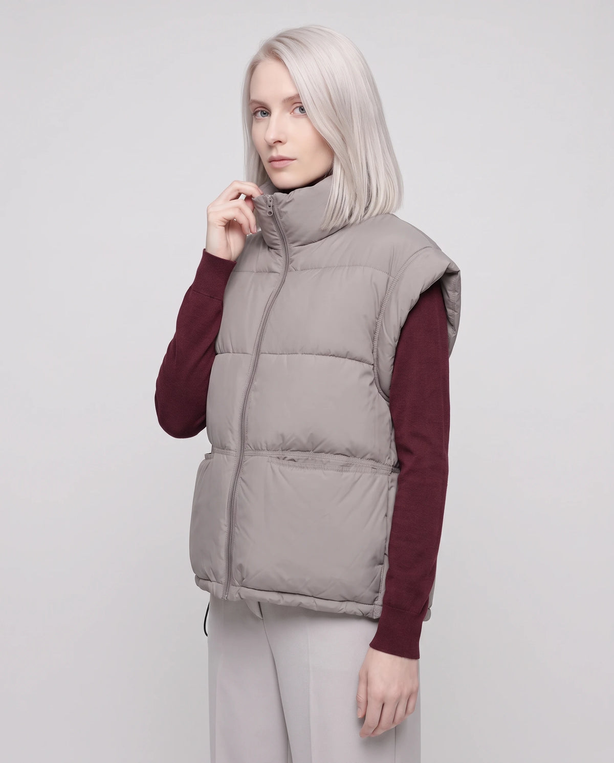 Gilet matelassé sans manches à poches plaquées Anceline en Gris Taupe, col remonté et zippé jusqu'au menton, vue de trois quarts
