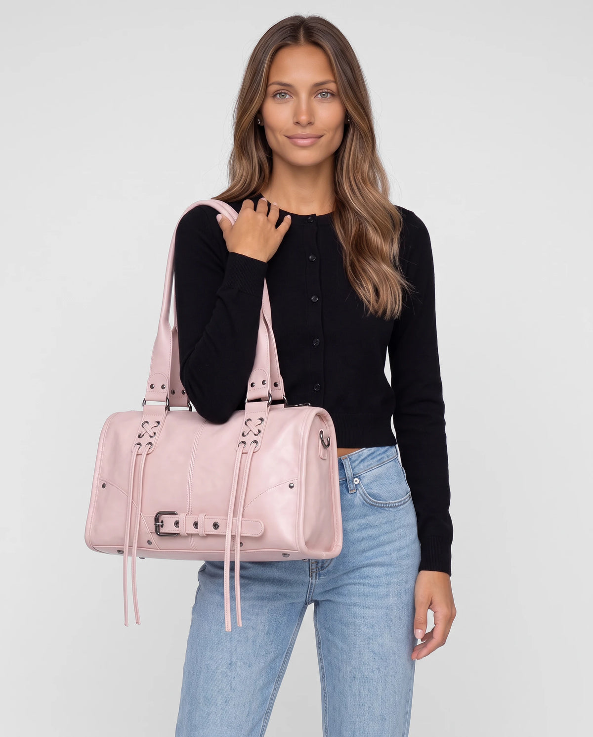 Grand sac à main bowling bandoulière style motard à lacets Avril coloris Rose Poudré, porté à l'épaule par ses deux anses, sur un cardigan noir