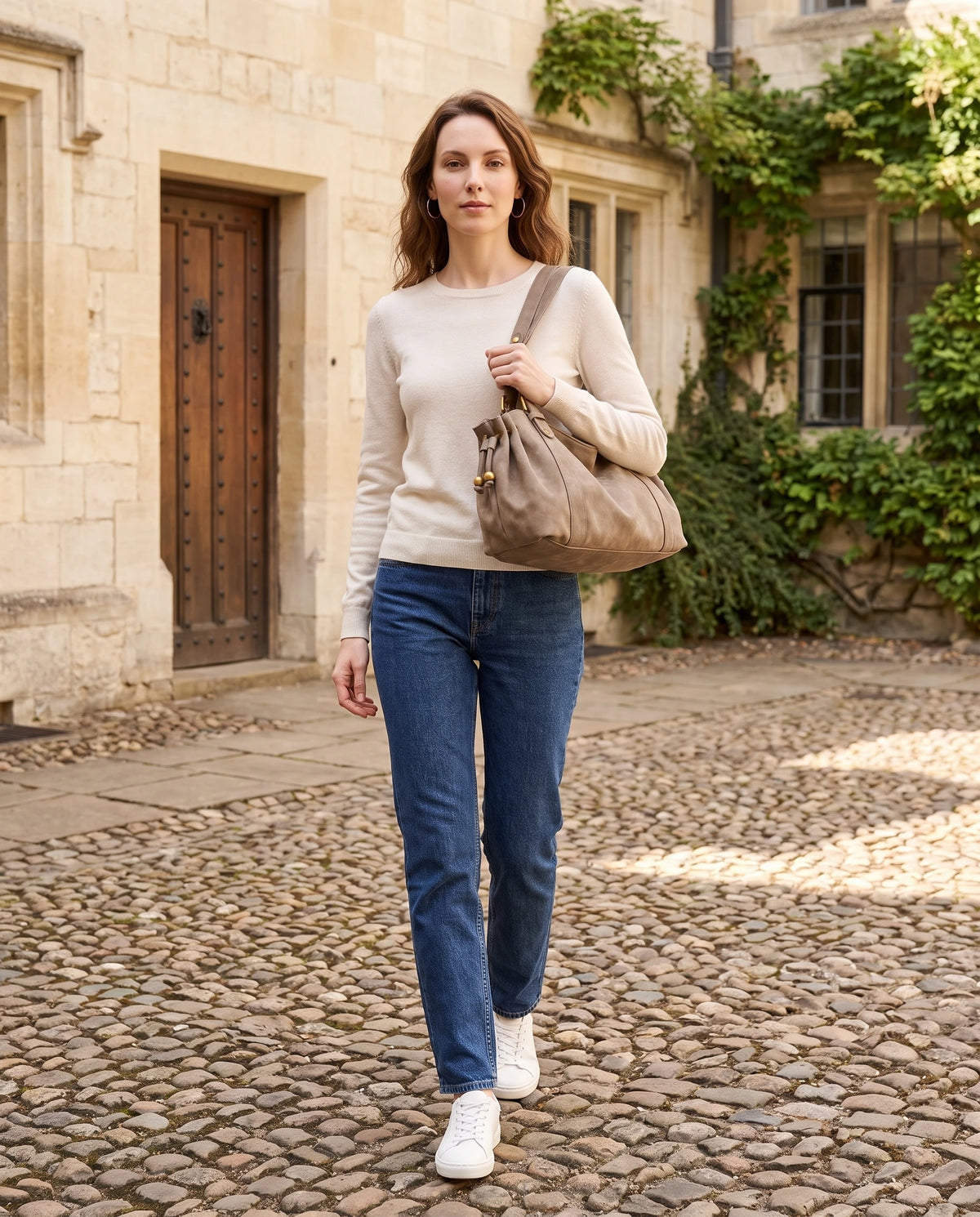 Grand sac à main de cours bowling en suédine Océane coloris Taupe, porté dans une cour pavée