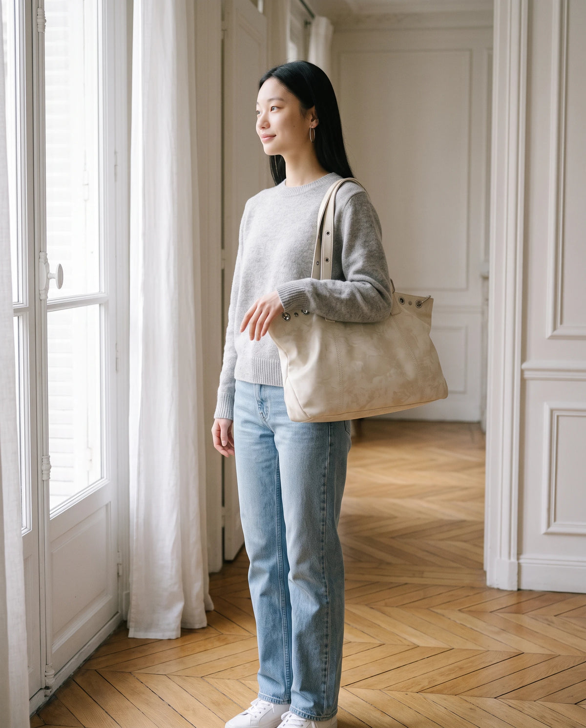 Grand sac à main cabas hobo vintage à œillets Billie coloris Blanc Cassé, porté à l'épaule dans un appartement parisien