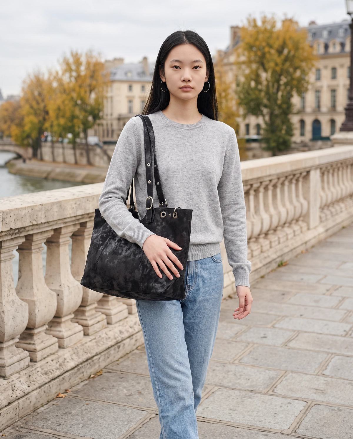 Grand sac à main cabas hobo vintage à œillets Billie coloris Noir, porté sur un pont de pierre en automne