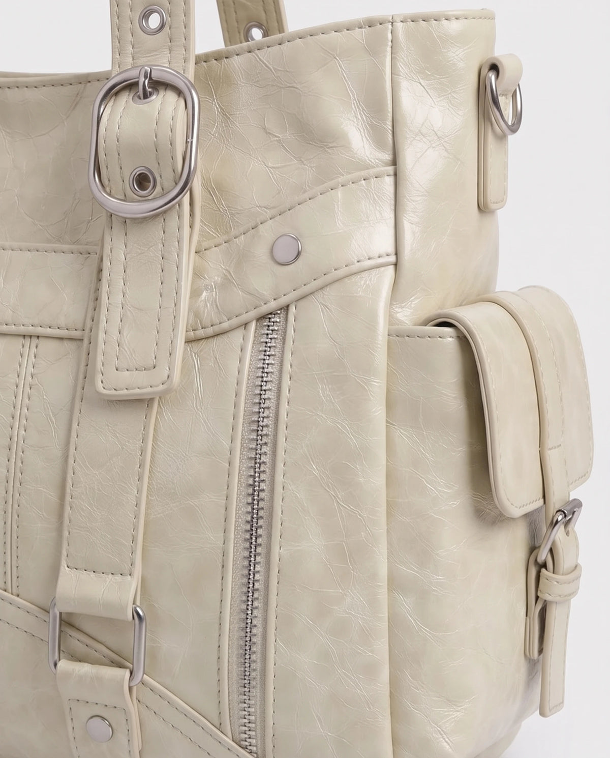 Grand sac à main cabas de cours style motard à boucles Pia coloris Crème, gros plan sur la boucle d'anse argentée, le zip vertical et la poche latérale à rabat sanglé