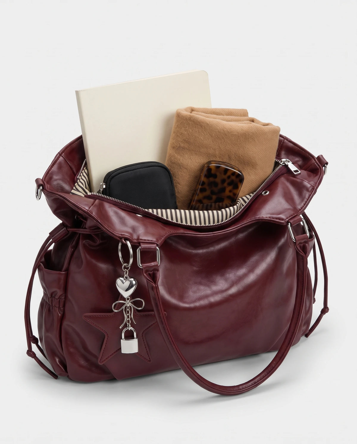 Grand sac à main hobo de cours bandoulière à breloque étoile Lyra coloris Bordeaux, intérieur garni d'un cahier A4, d'une écharpe, d'une pochette et d'un étui à lunettes