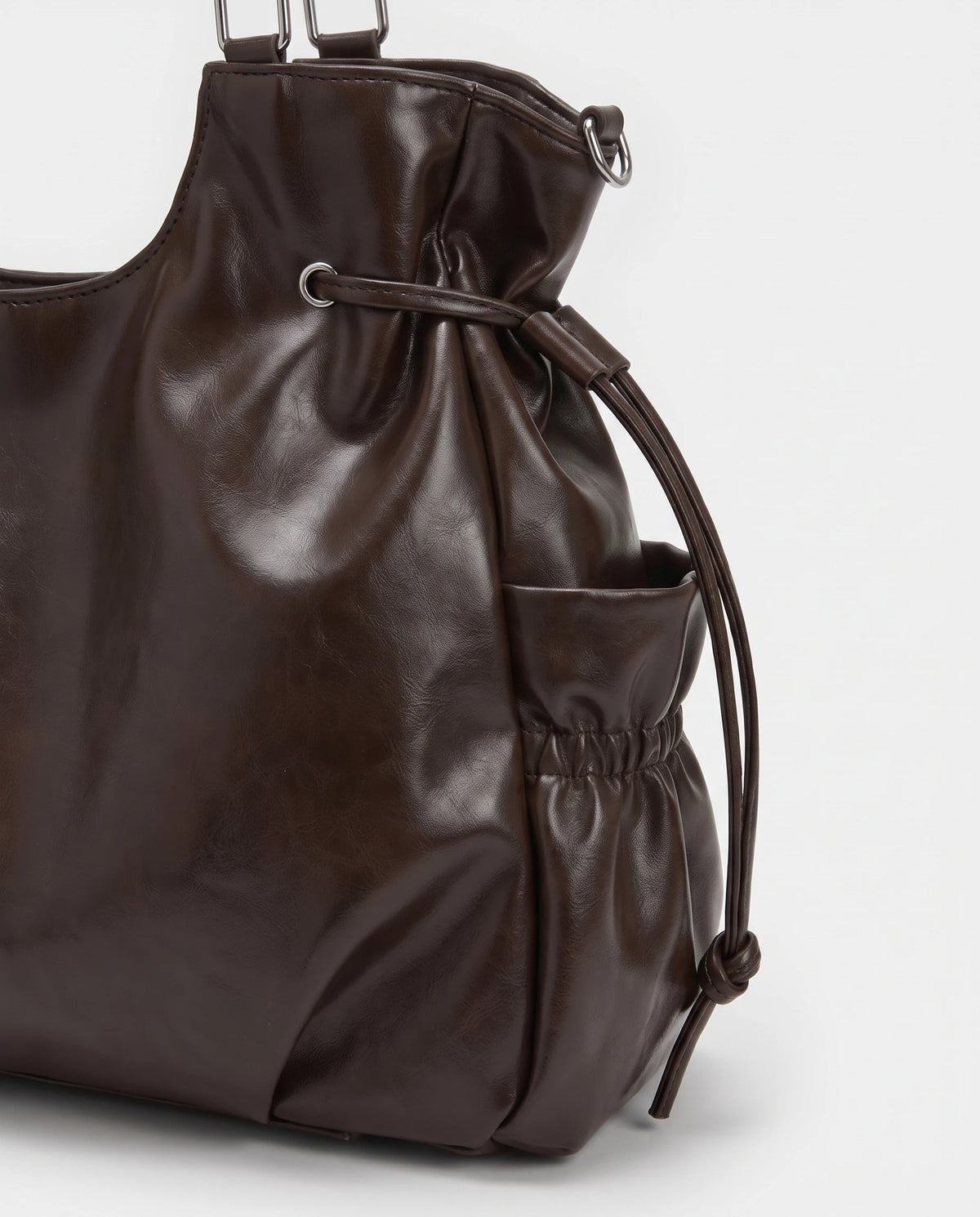 Grand sac à main hobo de cours bandoulière à breloque étoile Lyra coloris Chocolat Foncé, gros plan sur la poche latérale froncée, le cordon à embouts noués et l'œillet argenté