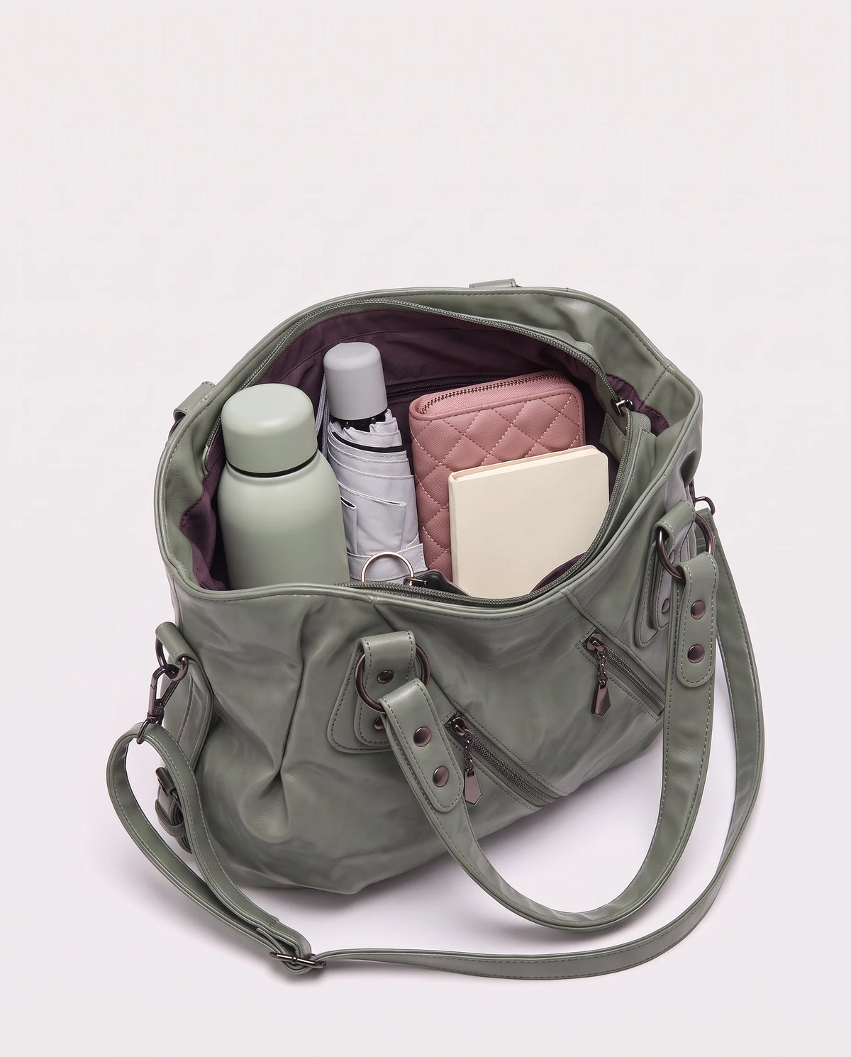 Grand sac à main hobo bandoulière style motard à zips Thelma coloris Vert Sauge, intérieur rempli d'une gourde, d'un parapluie pliant, d'un portefeuille et d'un carnet
