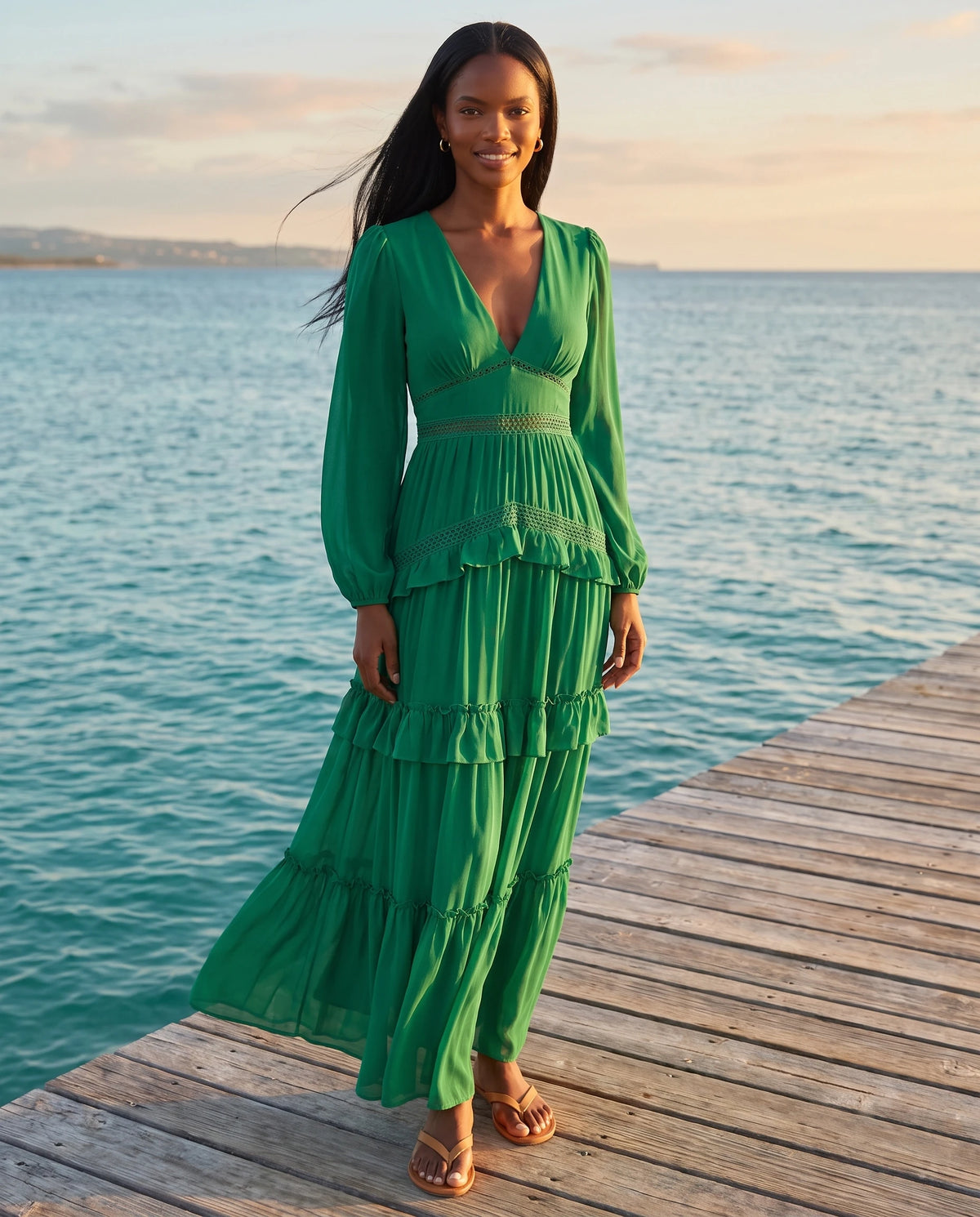Langes Boho-Kleid mit Volants und Häkelborten Inaya in Smaragdgrün, auf einem Steg am Meer getragen