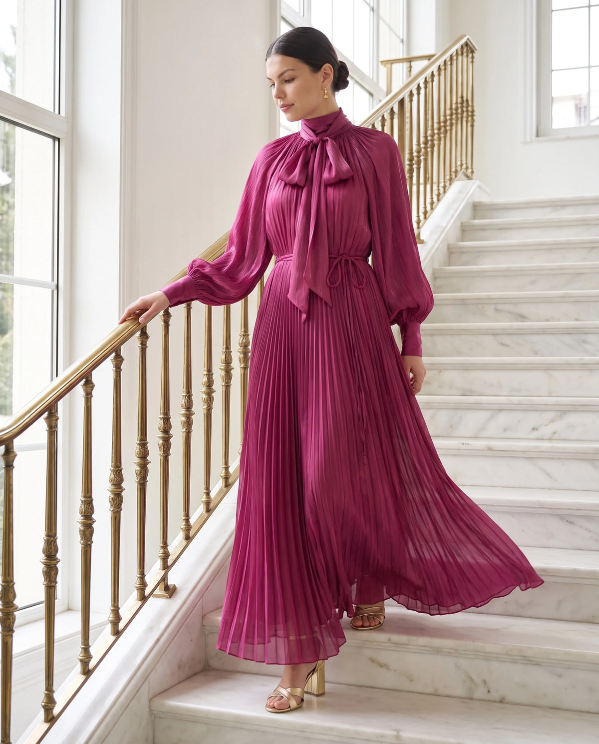Robe longue plissée à col lavallière et manches chauve-souris Antonia en Fuchsia, portée dans un escalier de marbre
