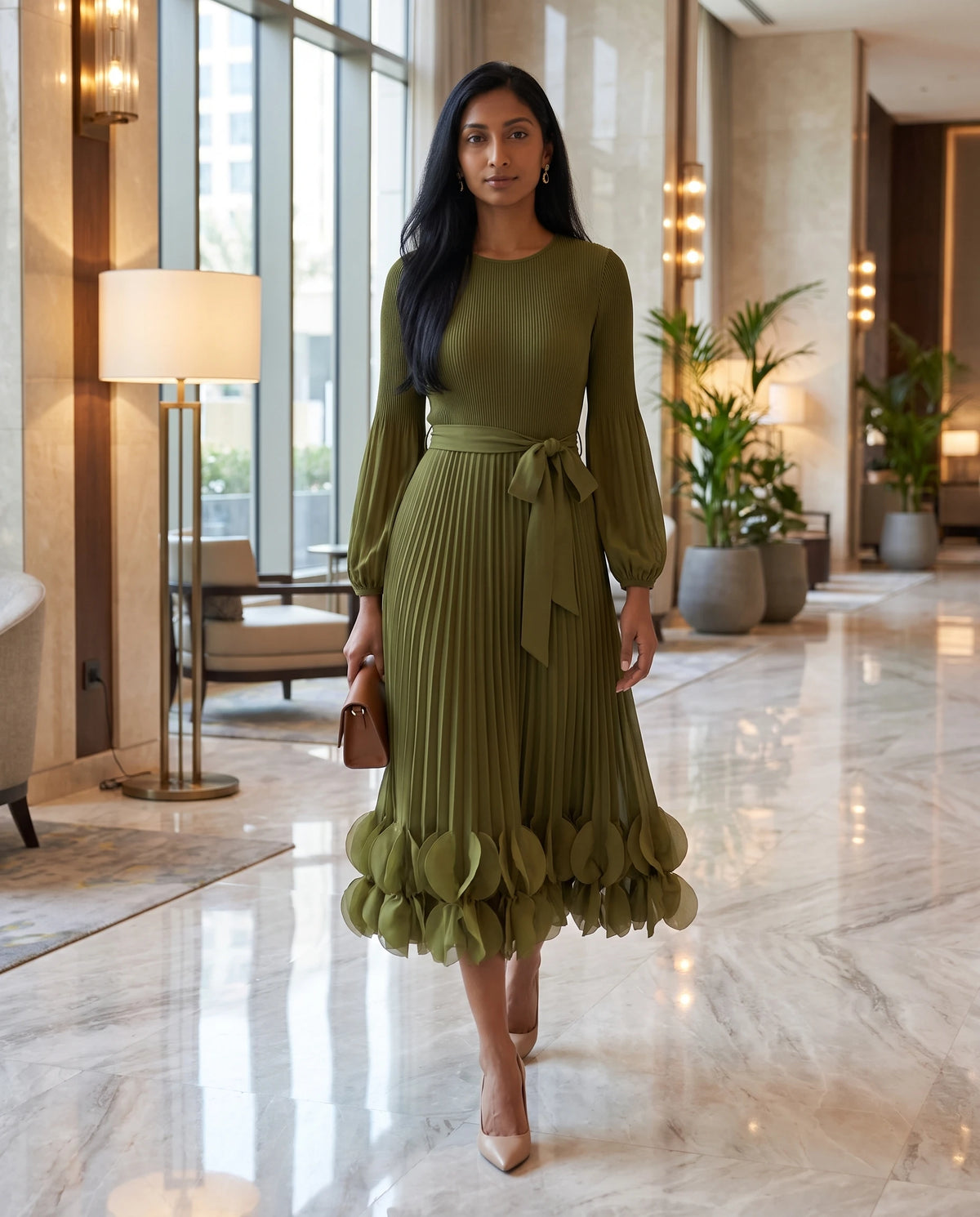 Plissee-Midikleid mit Blütenblatt-Saum Julienne in Olivgrün, in einer Hotellobby aus Marmor getragen
