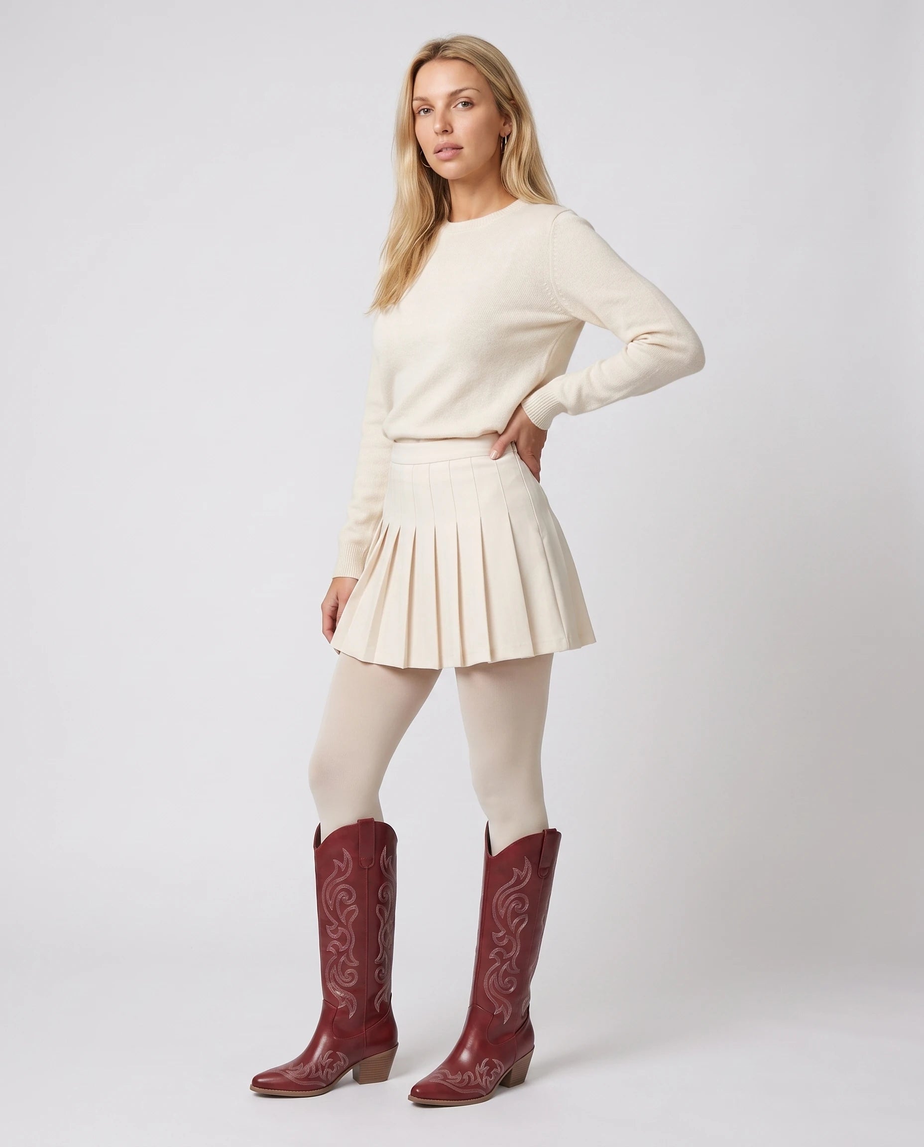 Bottes santiags hautes brodées Ghislaine — Rouge Grenat, portées en plein pied studio avec une jupe plissée écrue