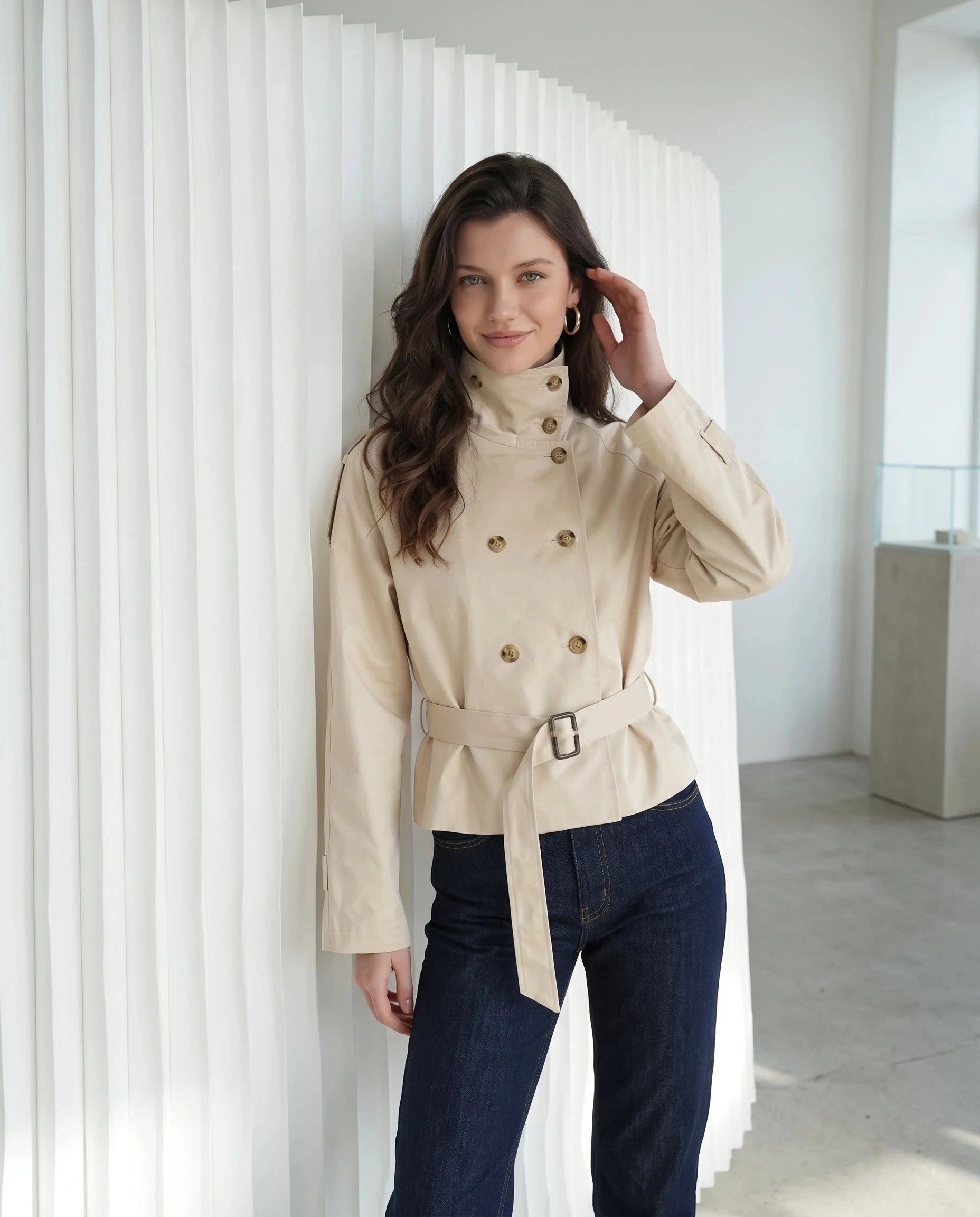 Trench court beige Louison, porté dans un intérieur lumineux