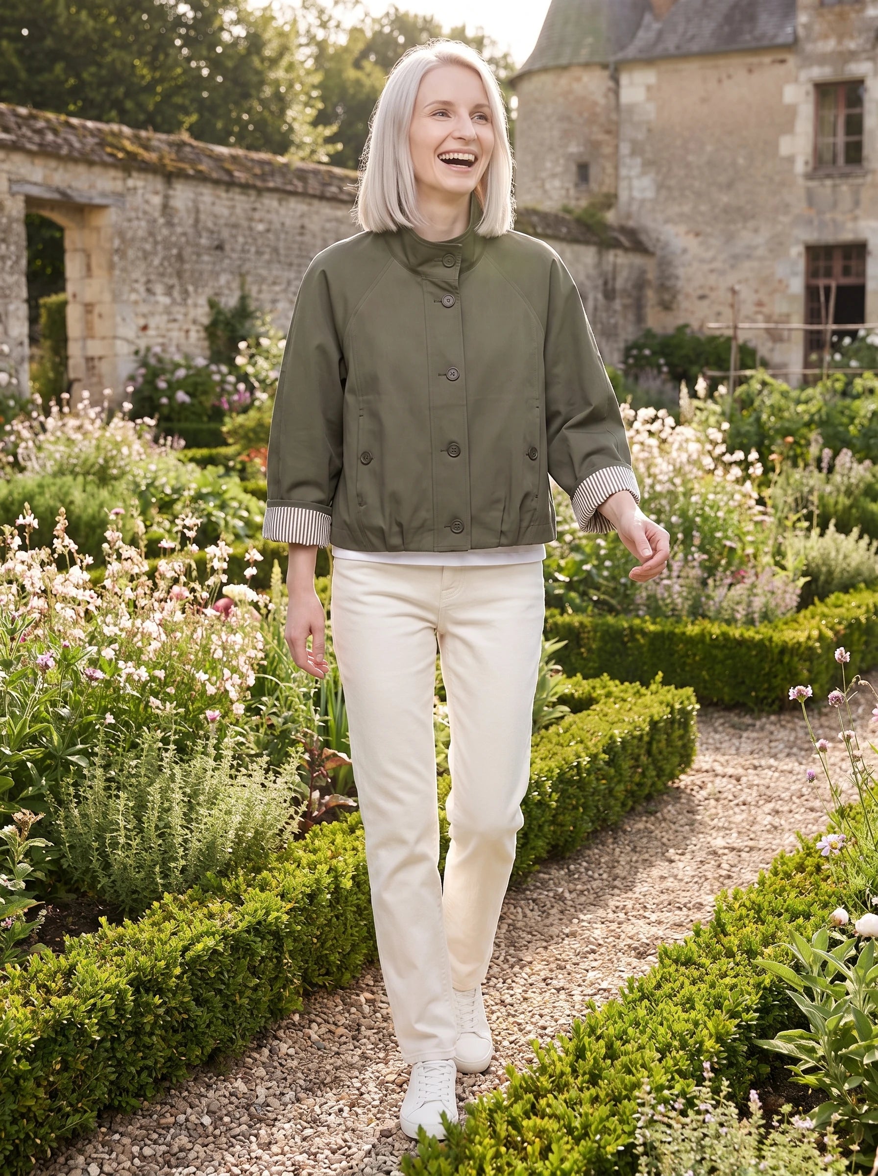 Trench court vert olive Raymonde, porté dans le potager fleuri d'un château