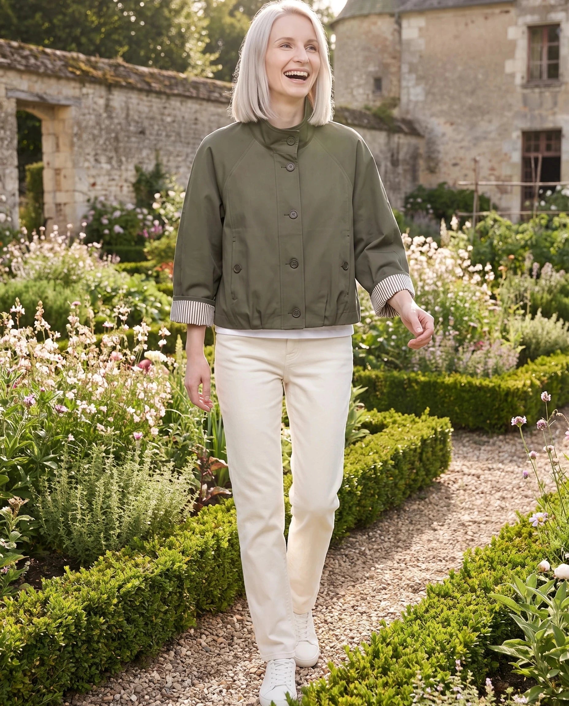 Trench court vert olive Raymonde, porté dans le potager fleuri d'un château