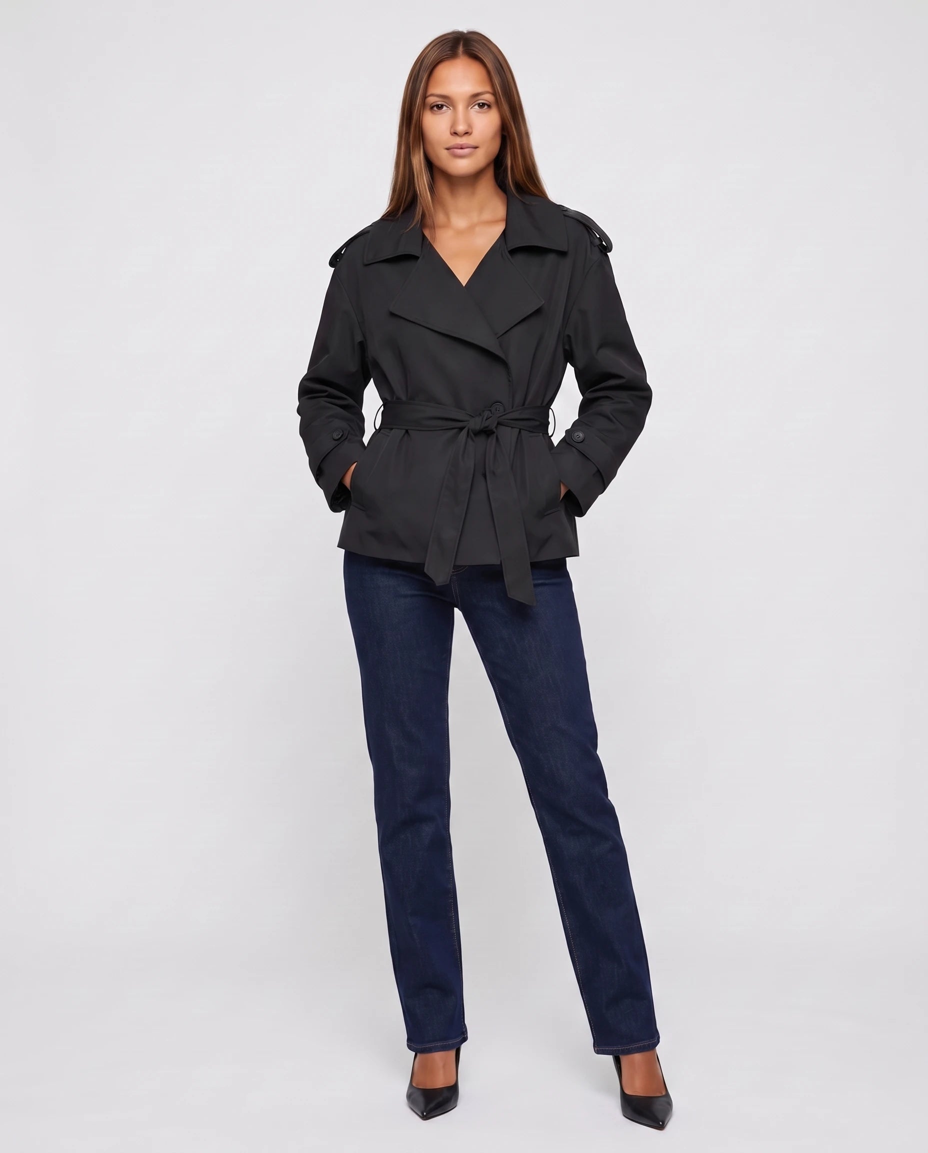 Trench court oversize noir Bettina, mains dans les poches, vue de face en studio