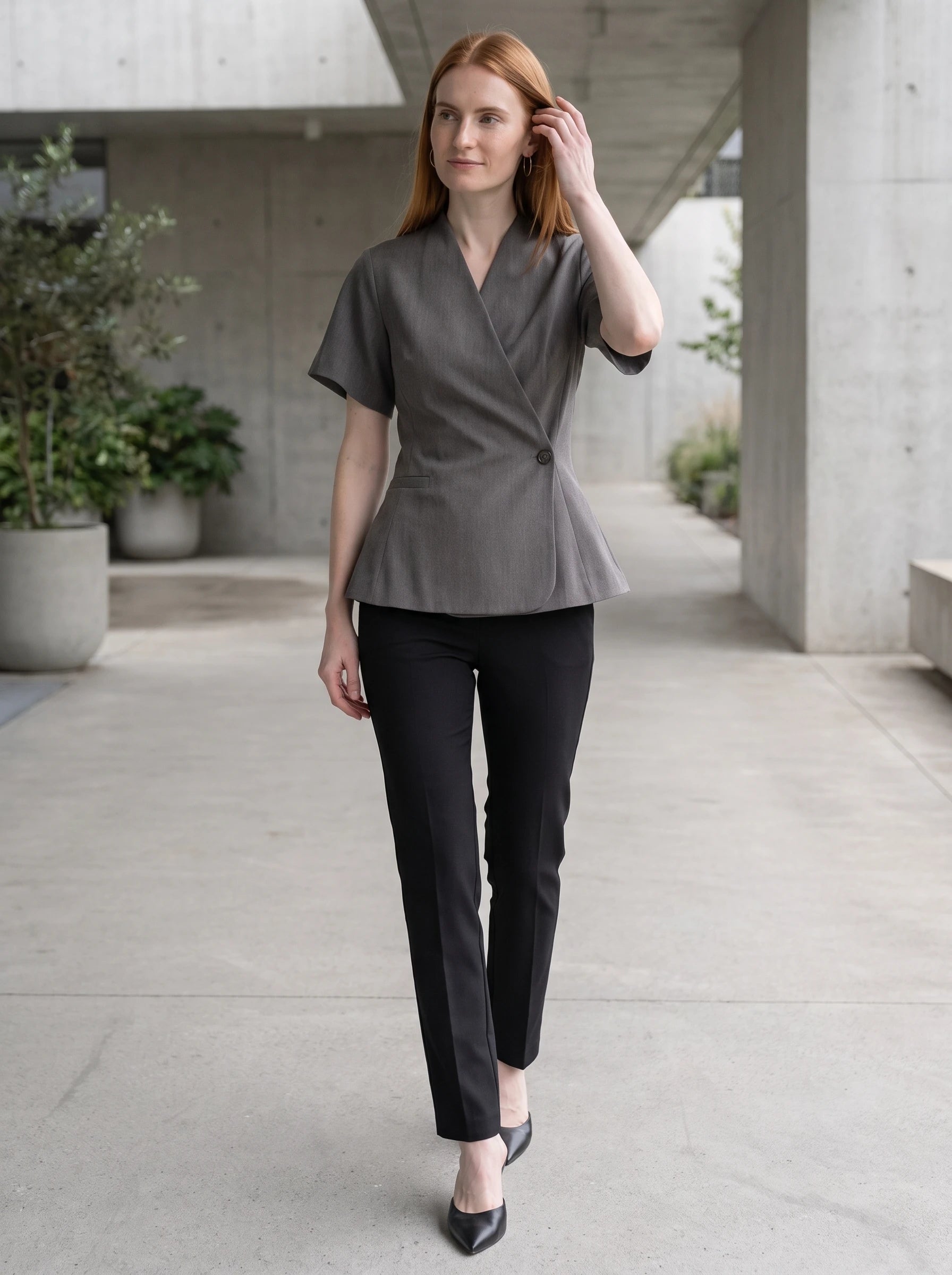 Veste cache-cœur gris chiné Célimène, portée dans un passage moderne en béton