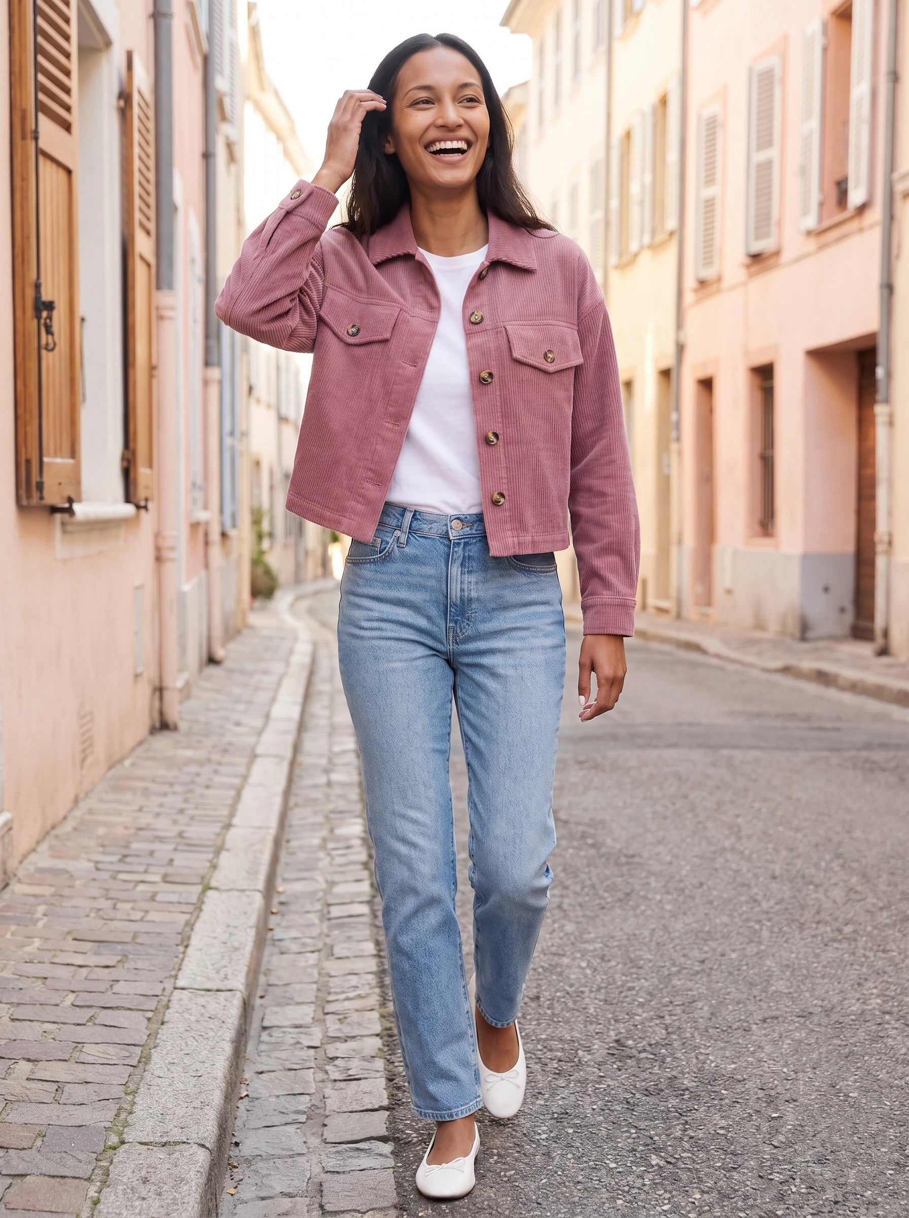 Veste chemise en velours côtelé vieux rose Josette, portée dans une rue aux façades pastel