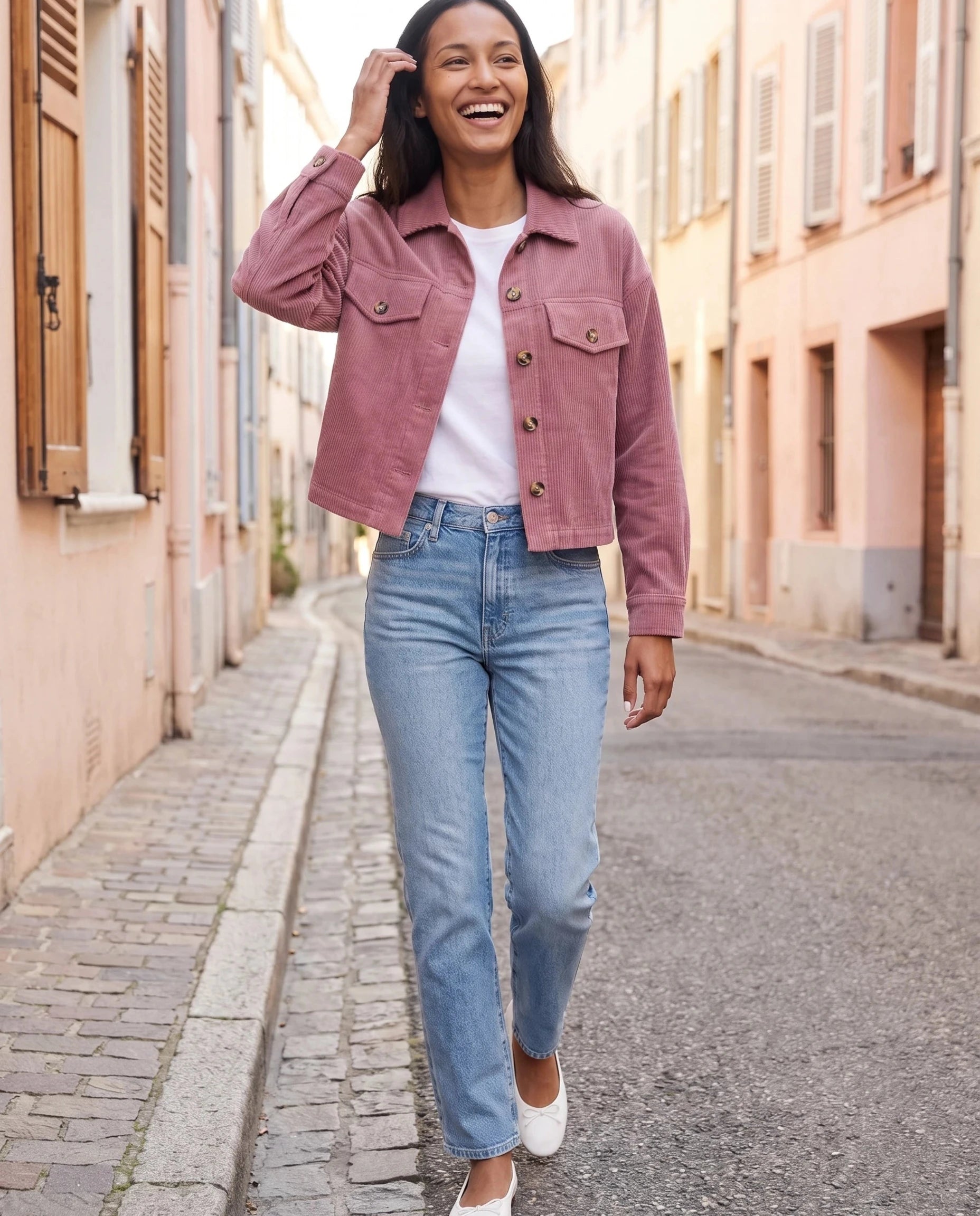 Veste chemise en velours côtelé vieux rose Josette, portée dans une rue aux façades pastel