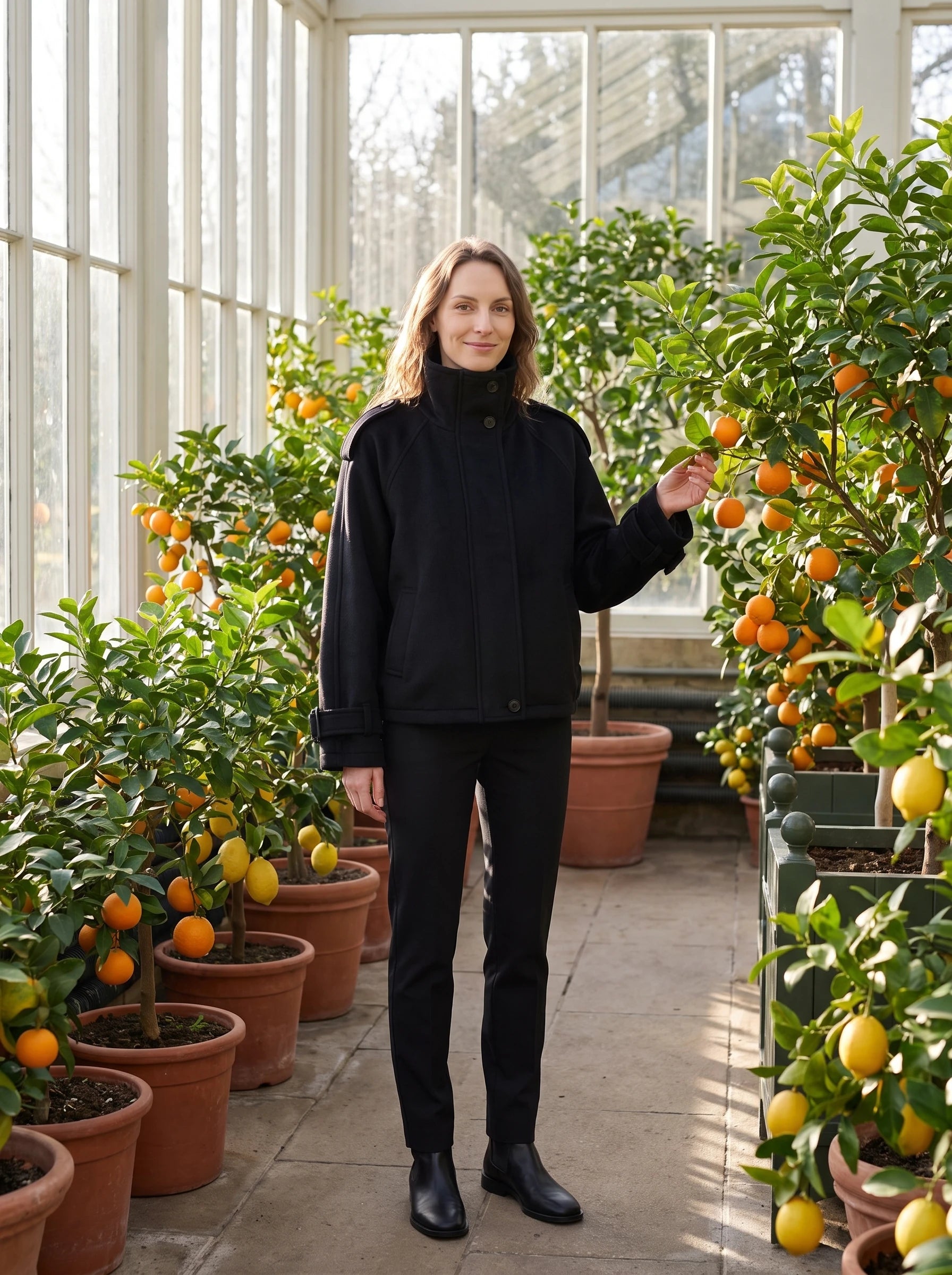 Veste cocon en lainage noir Josiane, portée dans une orangerie aux agrumes