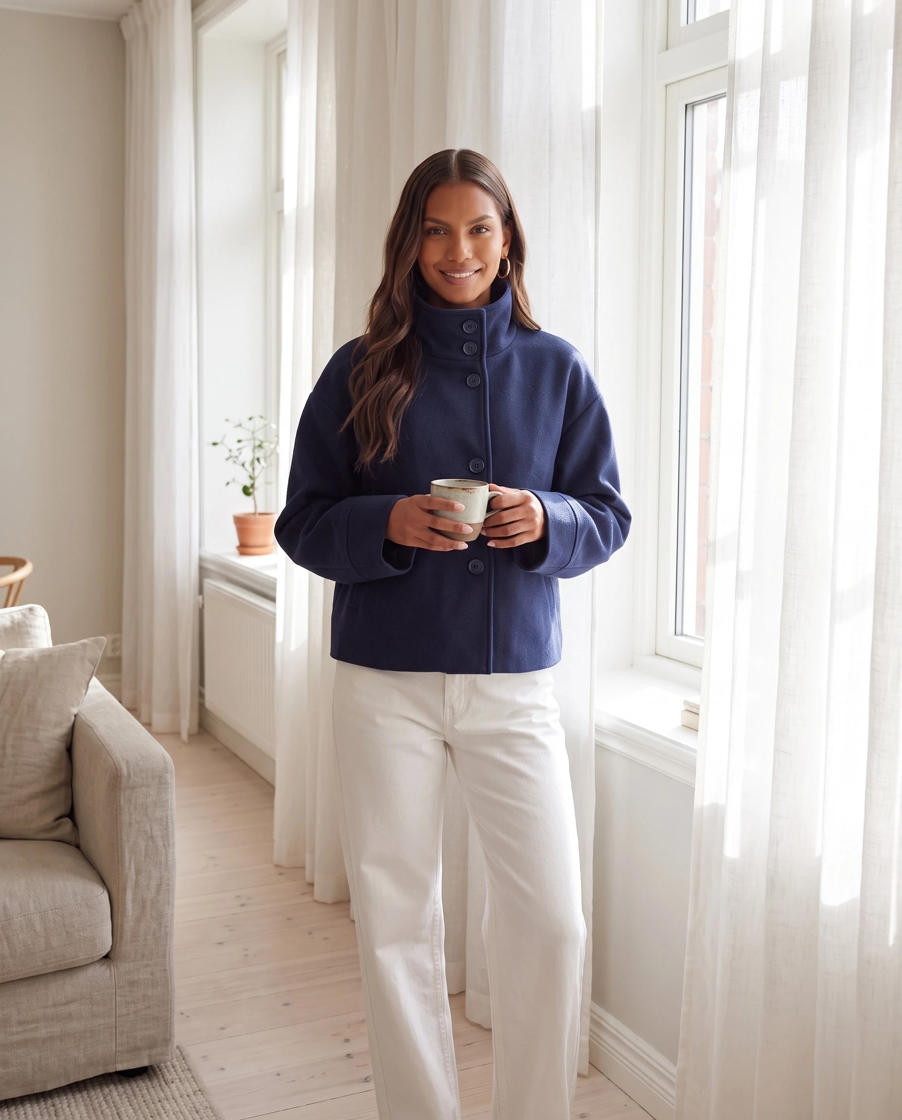 Veste courte à col montant bleu marine Théa, portée dans un intérieur scandinave