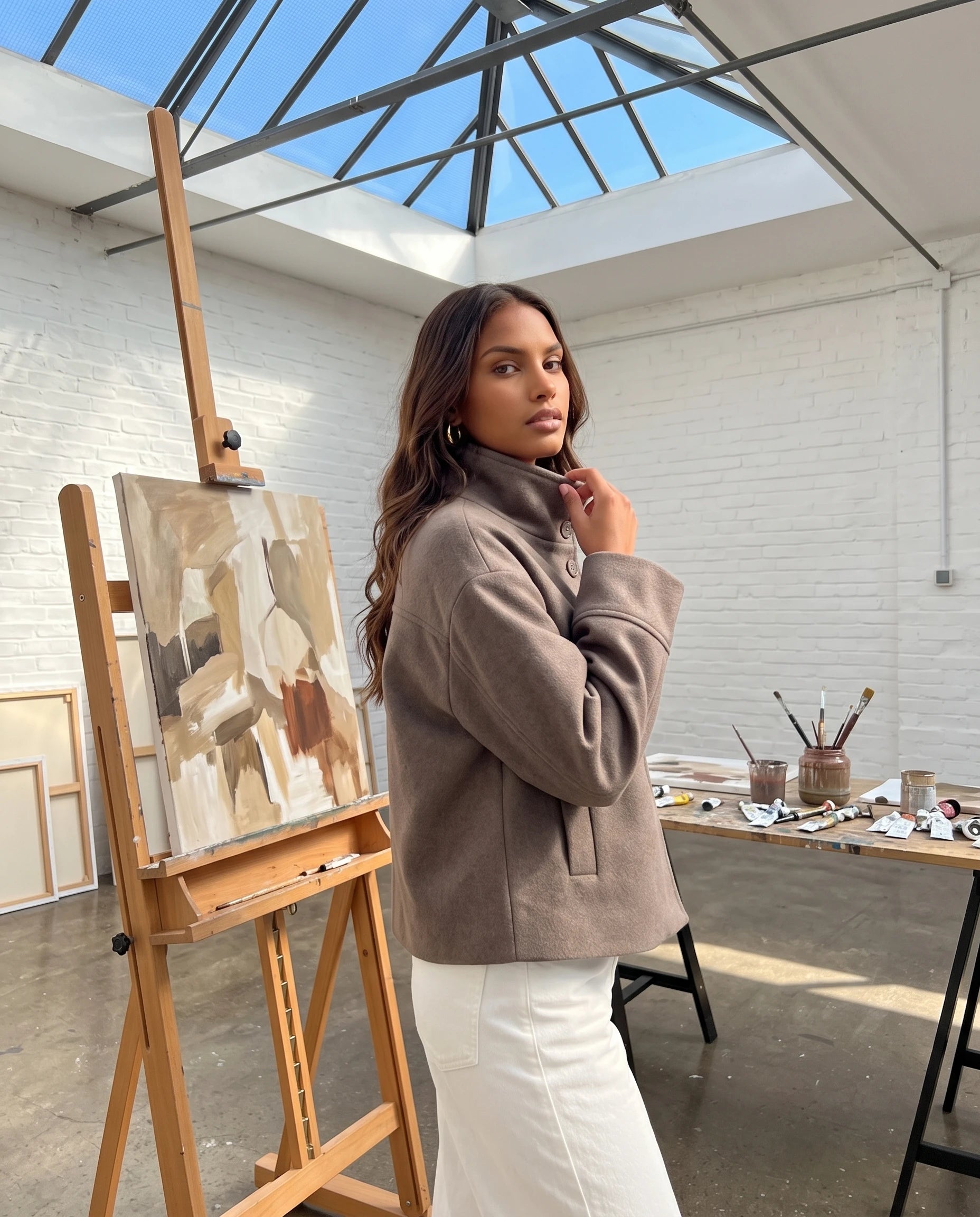 Veste courte à col montant taupe Théa, portée dans un atelier d'artiste