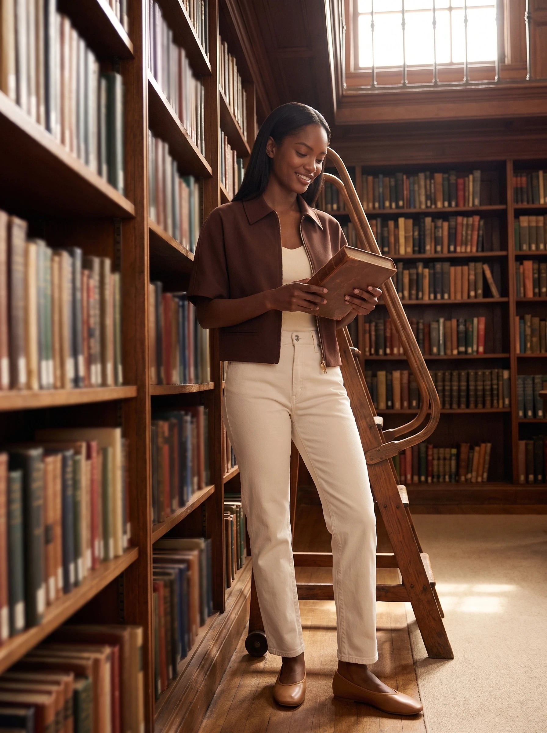 Veste courte zippée chocolat Gilberte, portée dans une bibliothèque ancienne