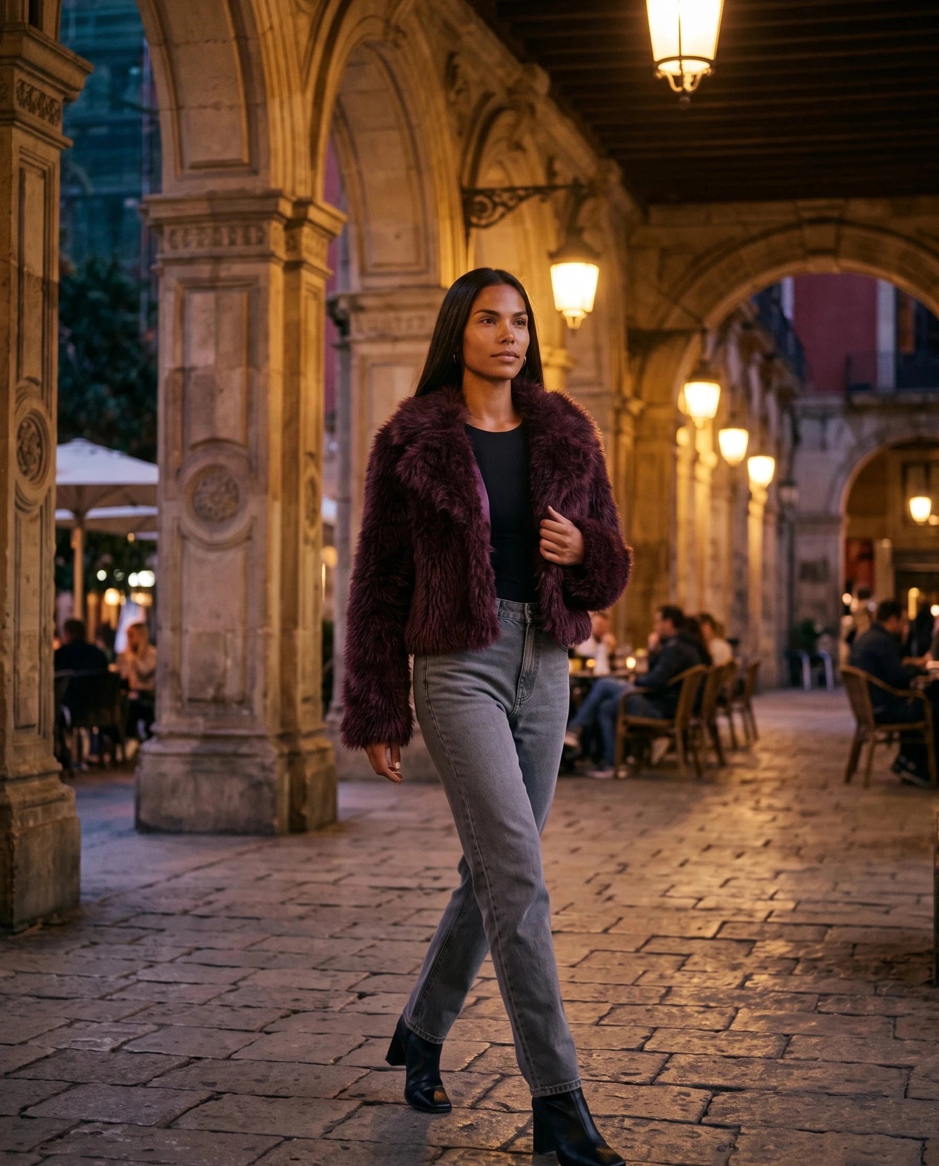 Veste en fausse fourrure bordeaux Léonilde, portée sous des arcades le soir