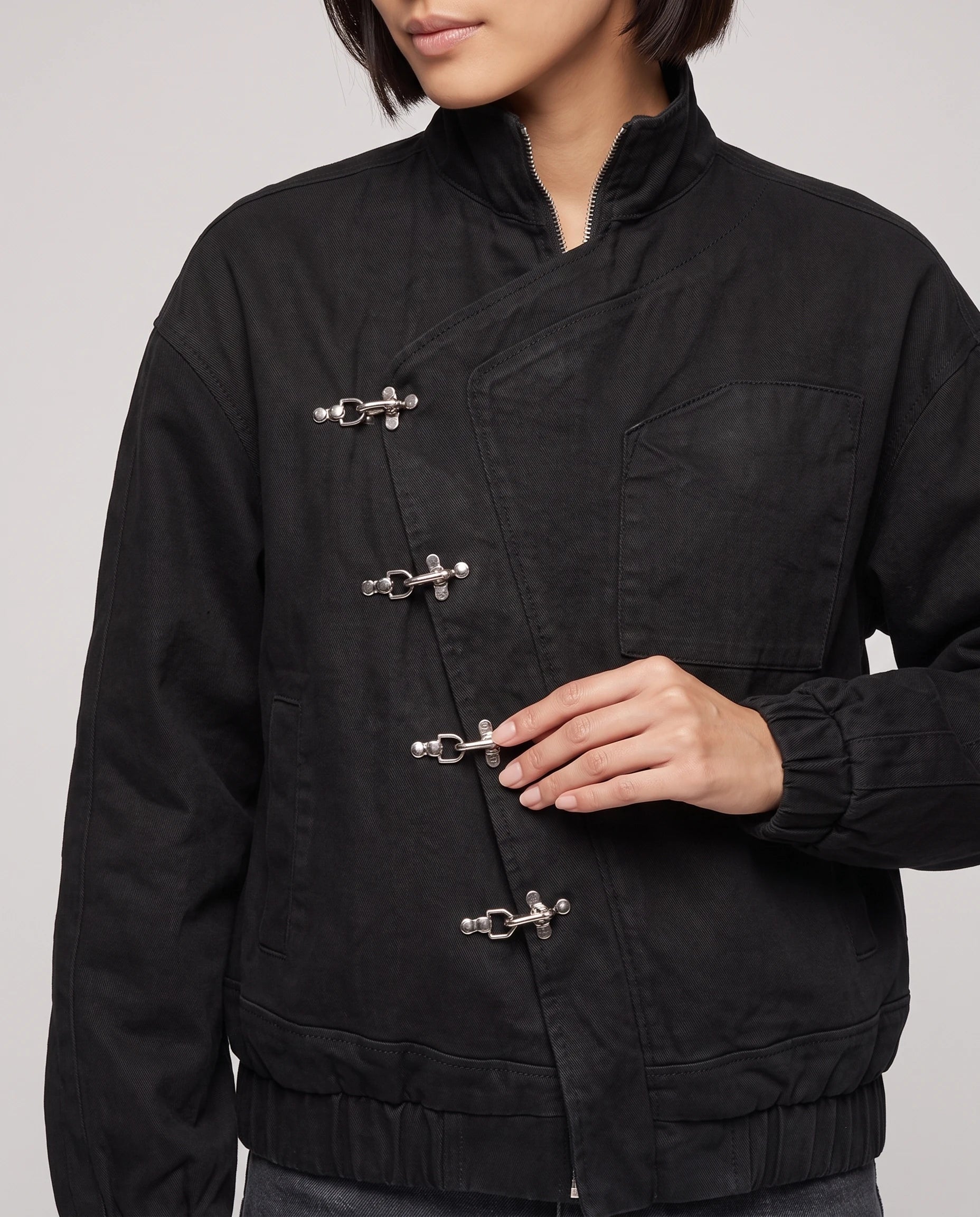 Veste noire Ingrid, détail des fermoirs pompier argentés et de la patte asymétrique