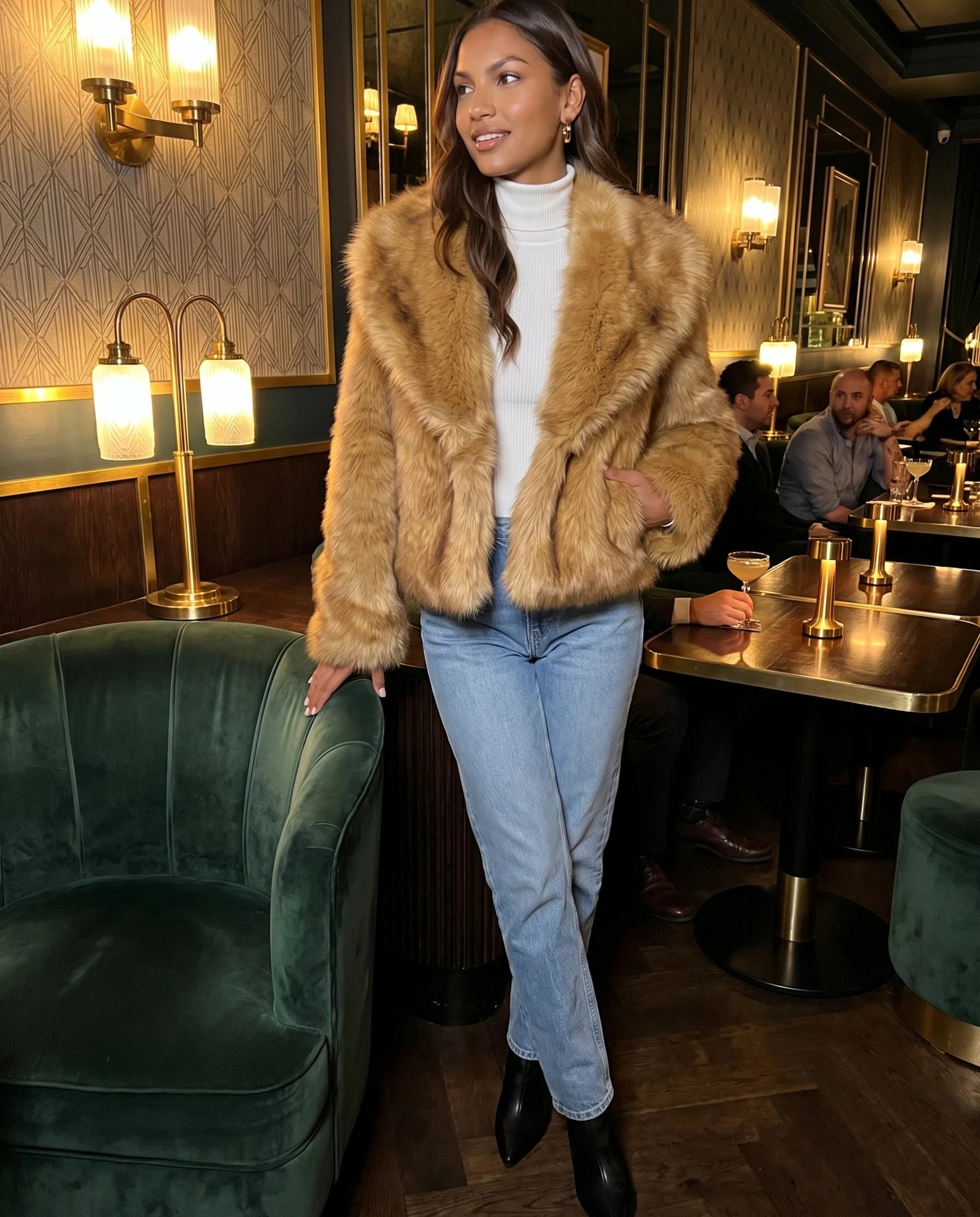 Veste fausse fourrure brun doré Nine, portée dans un bar art déco
