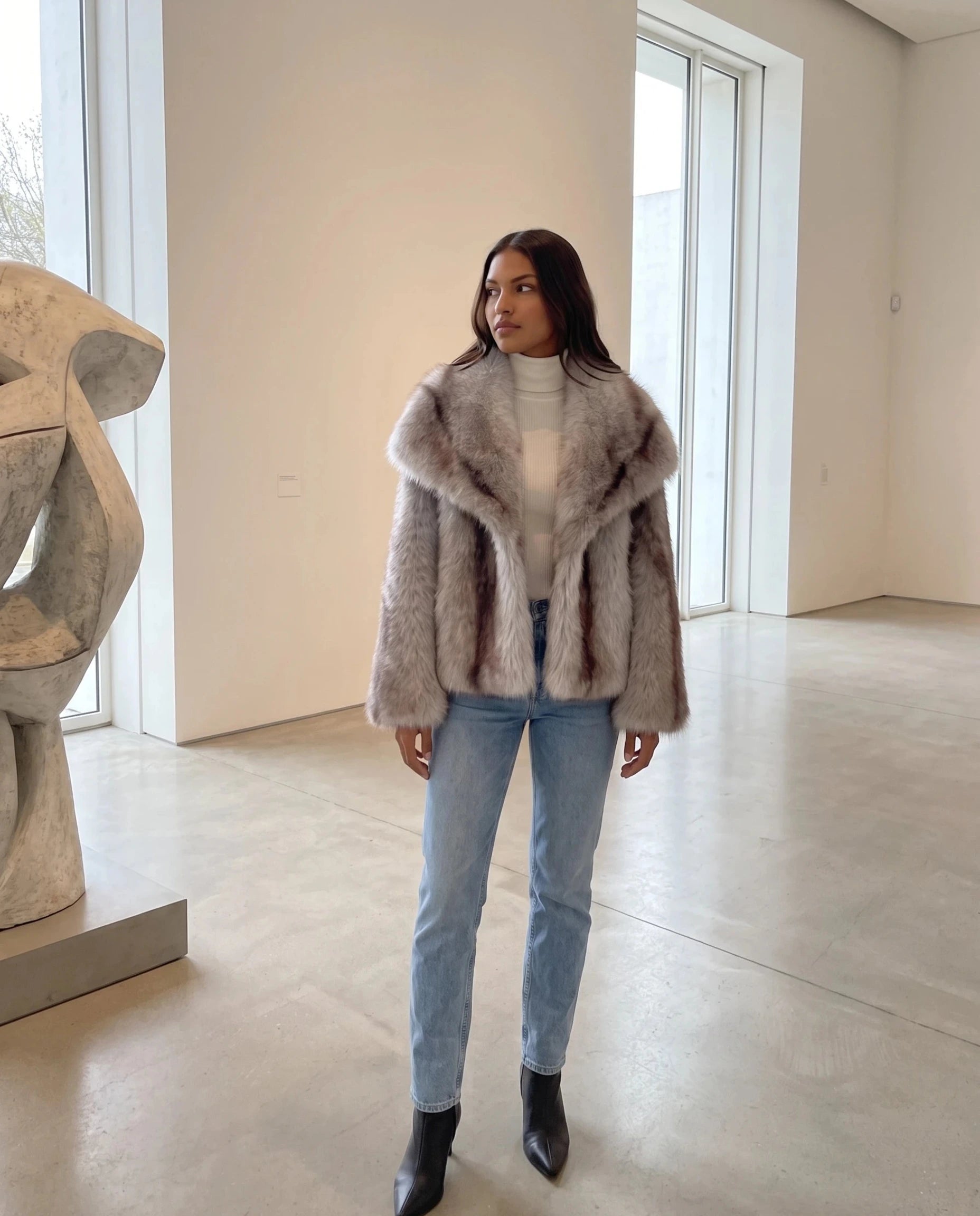 Veste fausse fourrure gris givré Nine, portée dans une galerie d'art lumineuse