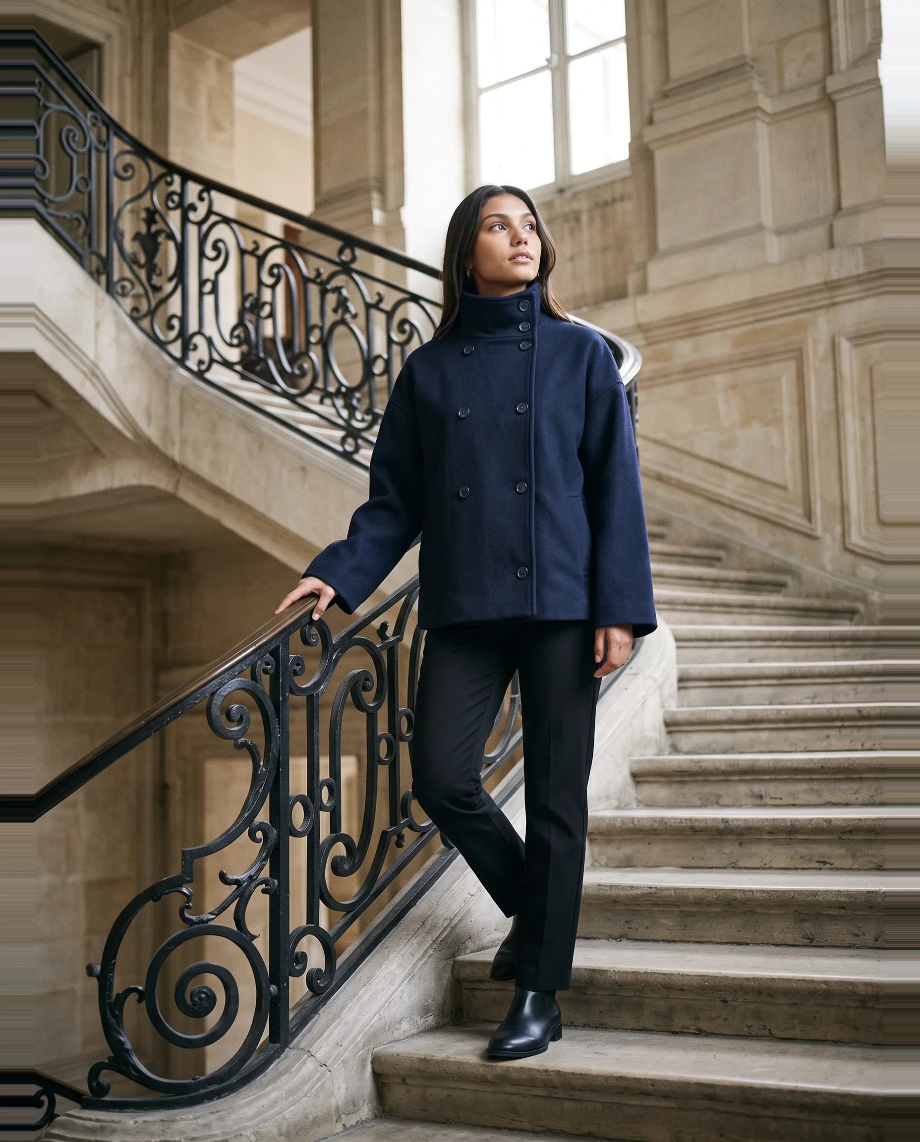 Veste en lainage bleu marine Rosalinde, portée dans un grand escalier de pierre