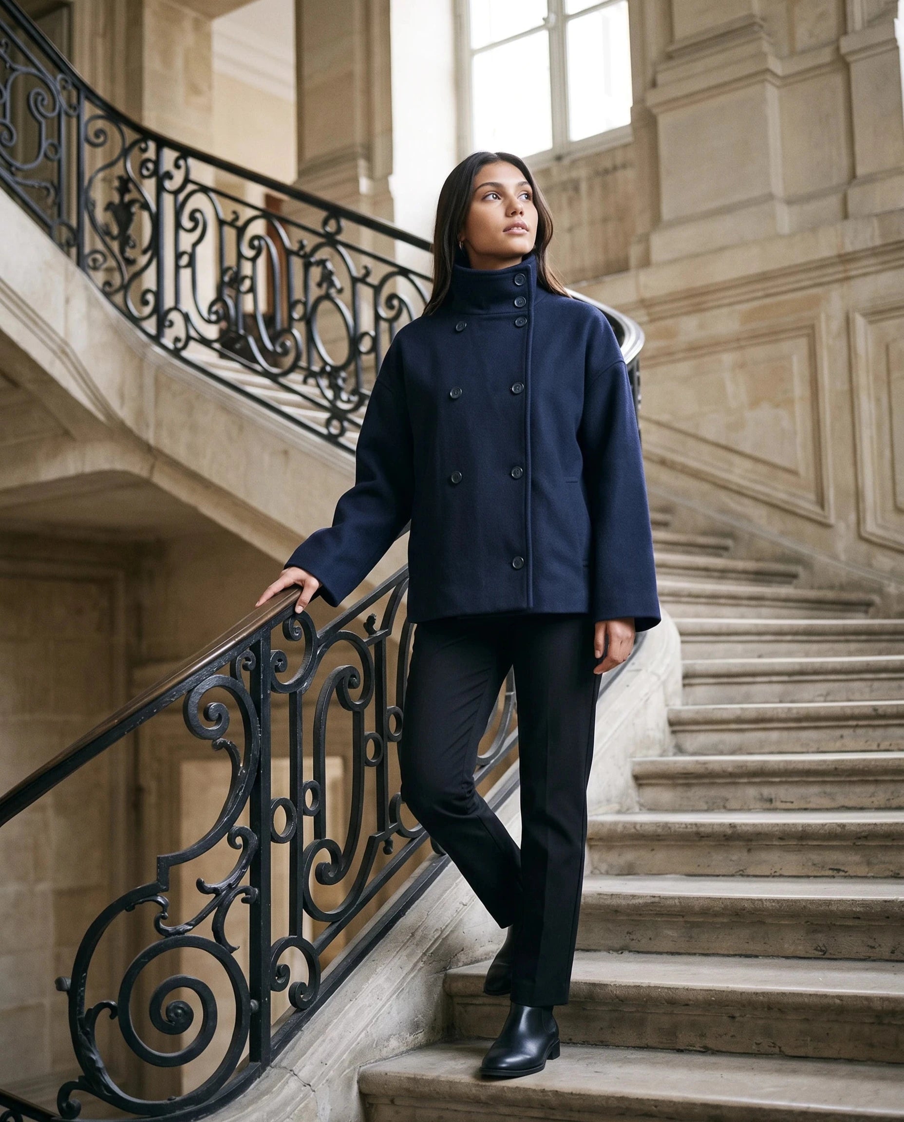 Veste en lainage bleu marine Rosalinde, portée dans un grand escalier de pierre