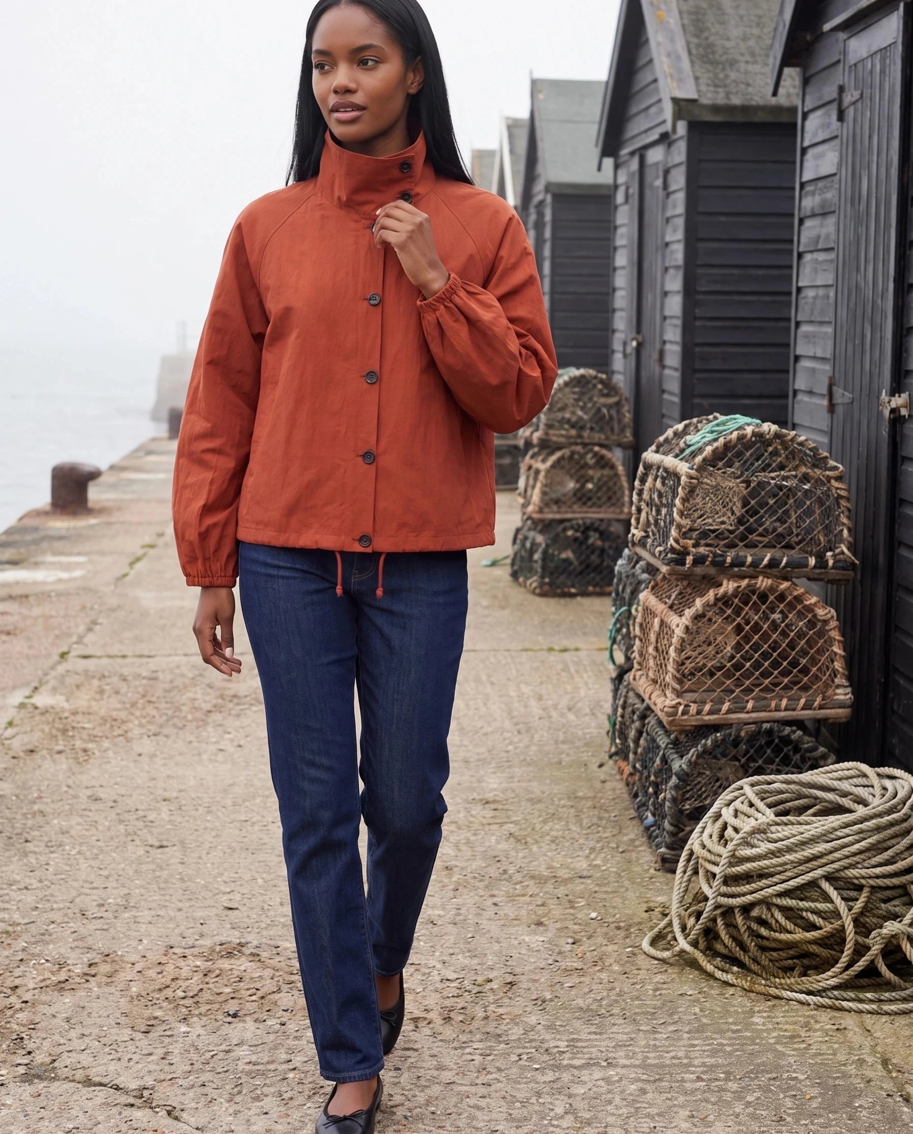 Veste légère rouge Euphrasie, portée sur une digue aux cabanes de pêcheurs