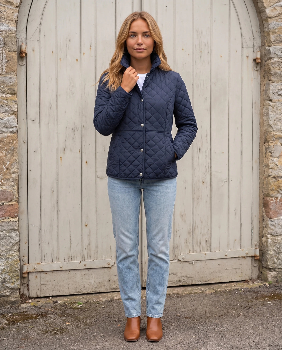 Veste matelassée à col chemise Ayla en Bleu Marine, portée devant une porte cochère en bois clair, col relevé