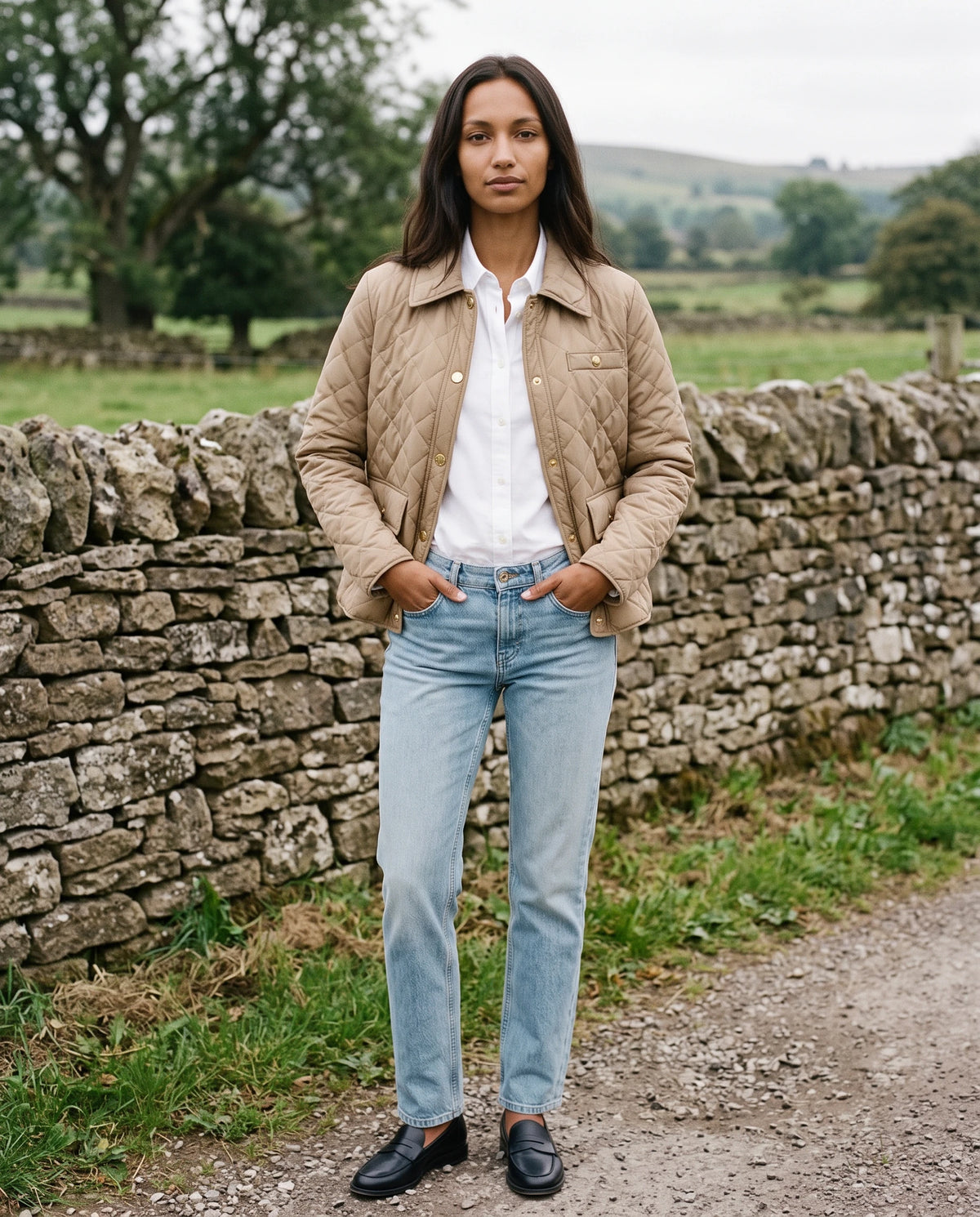 Veste matelassée à col chemise et pressions dorées Mélodie en Beige, portée devant un mur de pierre sèche, portée ouverte
