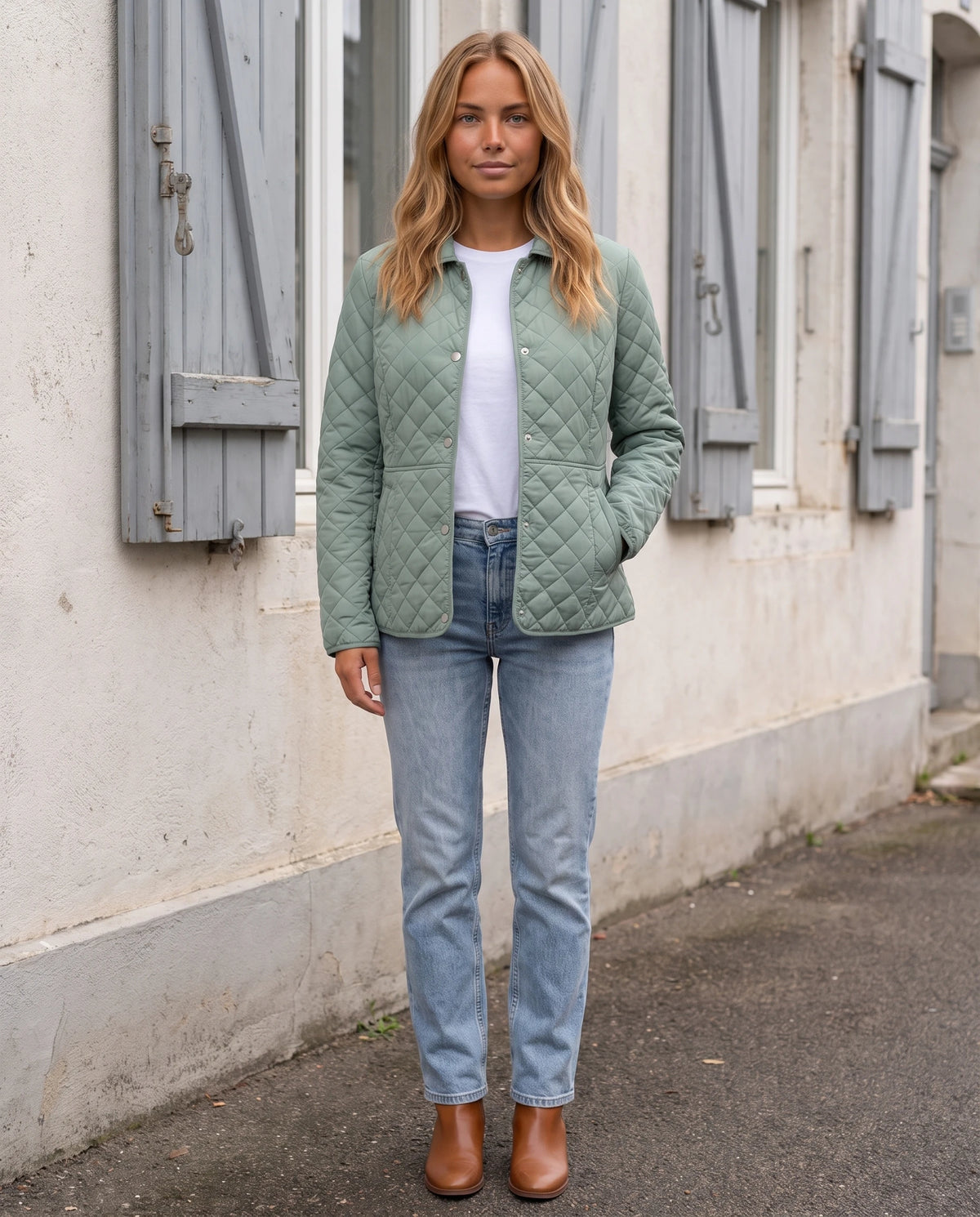 Veste matelassée à col chemise Ayla en Vert Sauge, portée devant une façade claire aux volets gris, portée ouverte