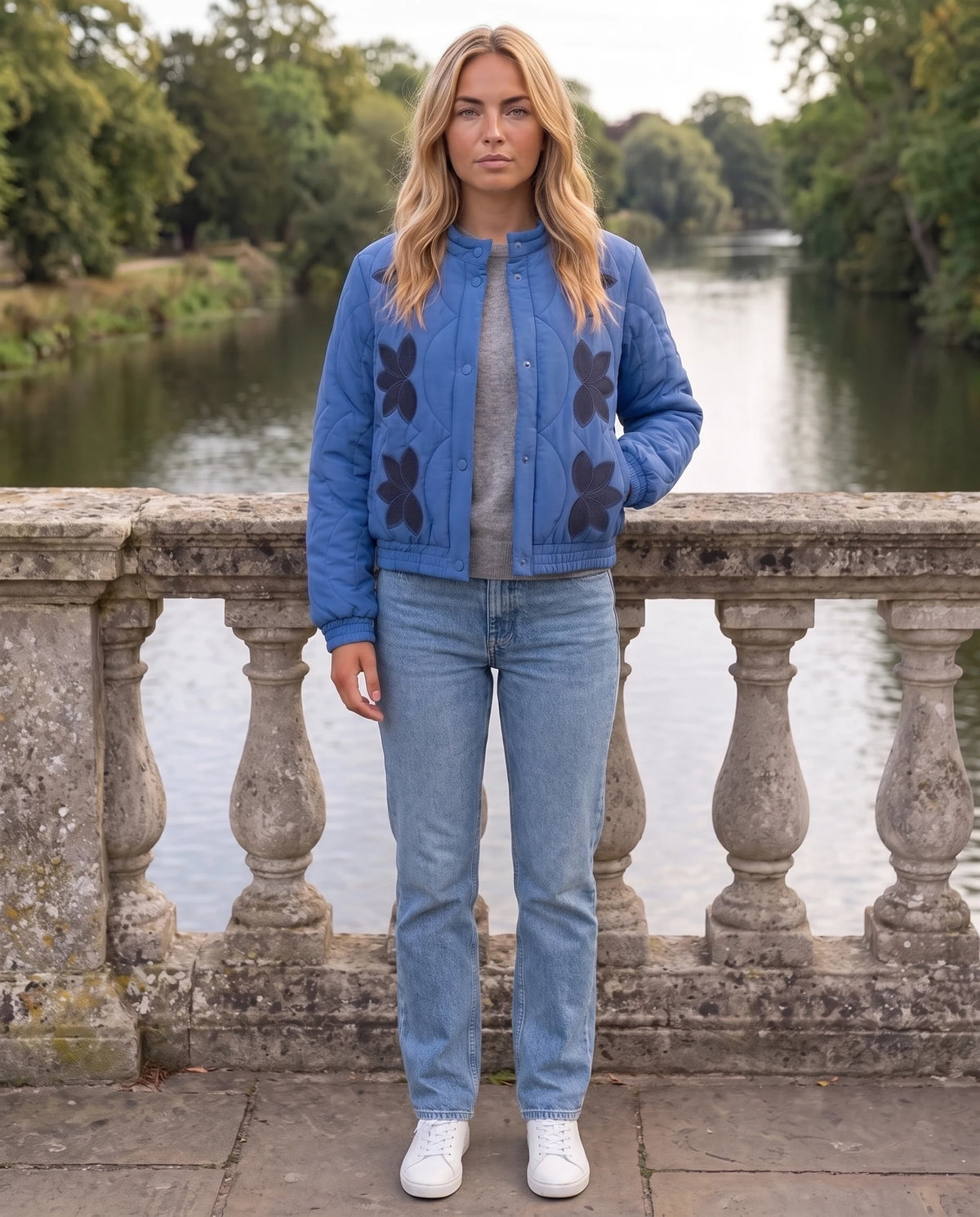 Veste matelassée col montant à pressions Julie en Bleu, portée sur un pont au-dessus d'une rivière