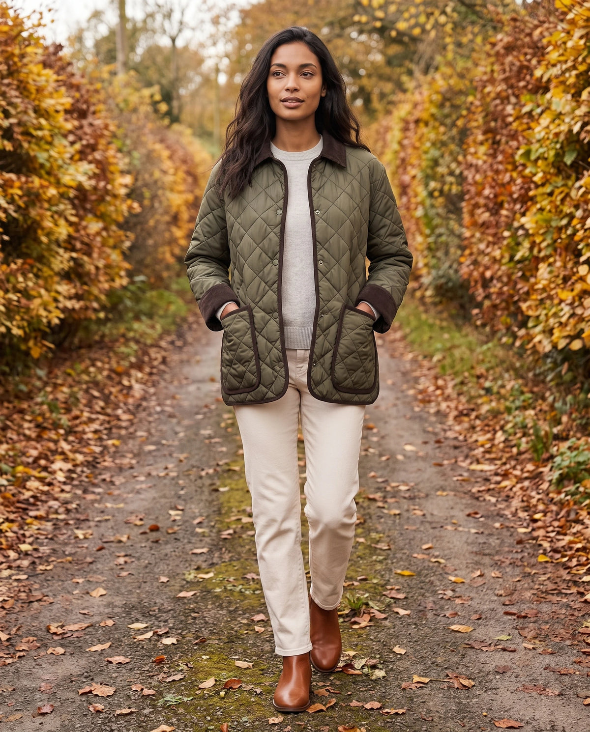 Veste matelassée à col velours côtelé Talia en Vert Olive, portée sur un chemin de campagne bordé de haies en automne
