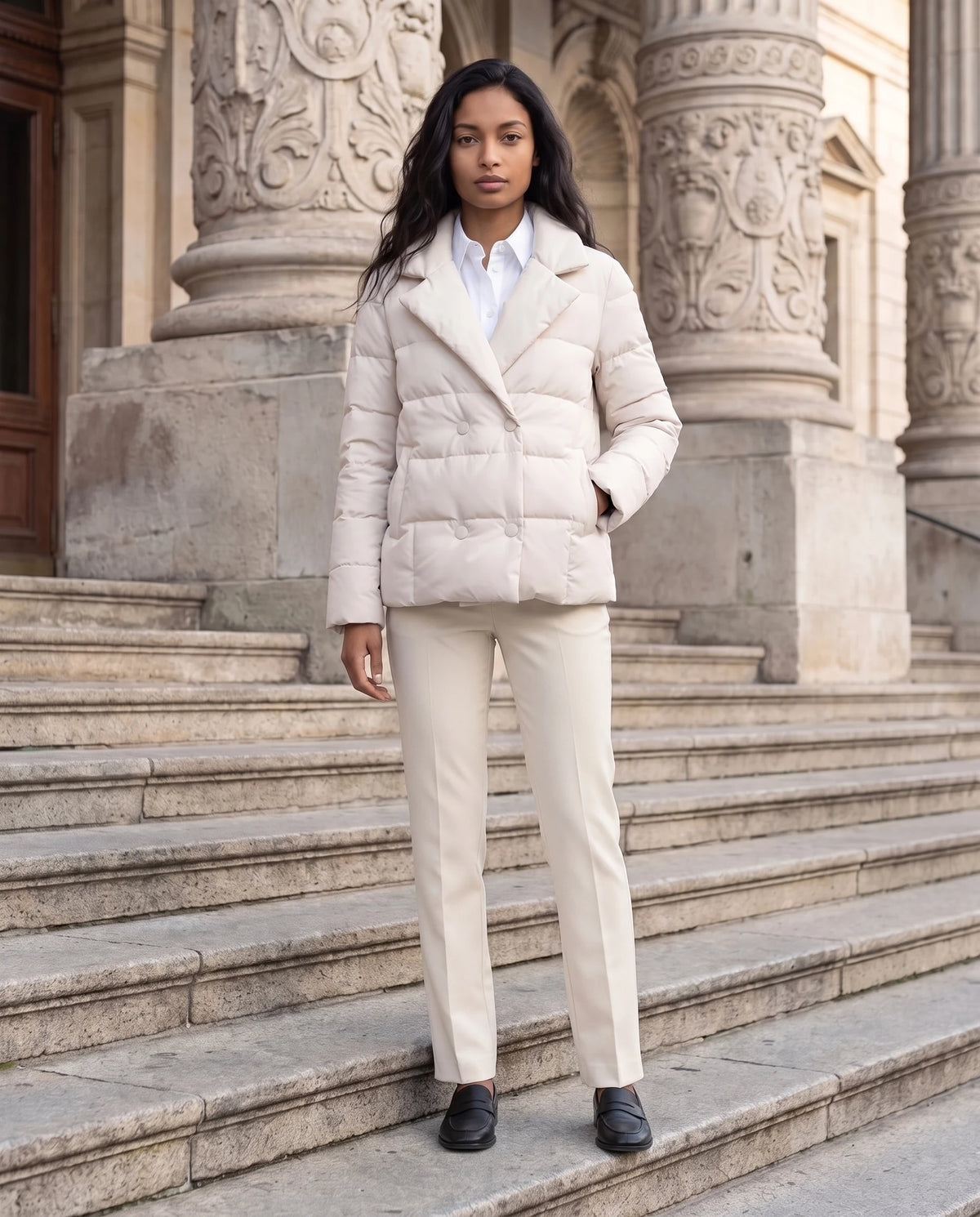 Veste matelassée courte col tailleur Agnès en Écru, portée sur les marches d'un théâtre en pierre