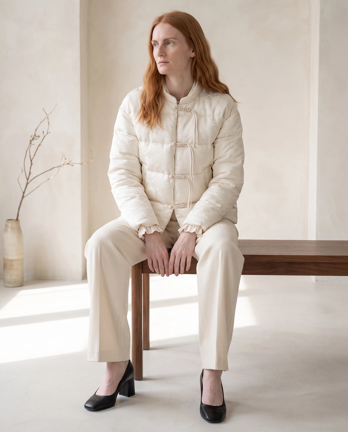 Veste matelassée jacquard à brandebourgs et col officier Dahlia écru, intérieur clair, assise sur un banc