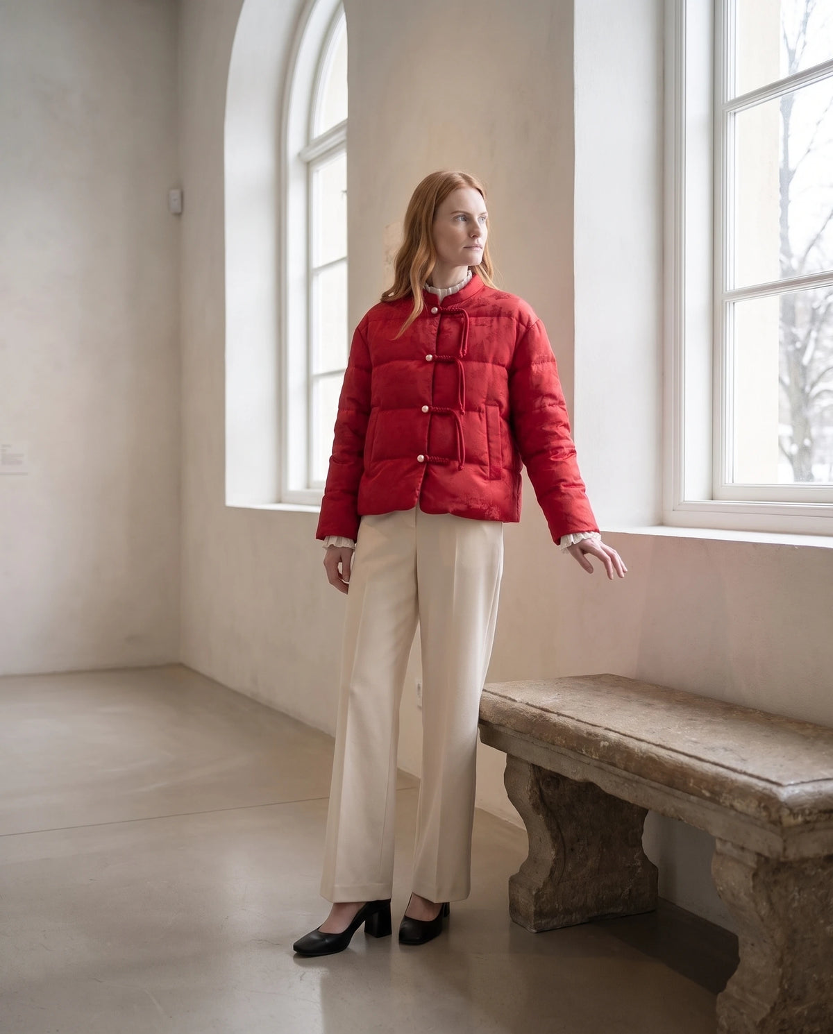 Veste matelassée jacquard à brandebourgs et col officier Dahlia rouge profond, galerie aux fenêtres cintrées, banc de pierre