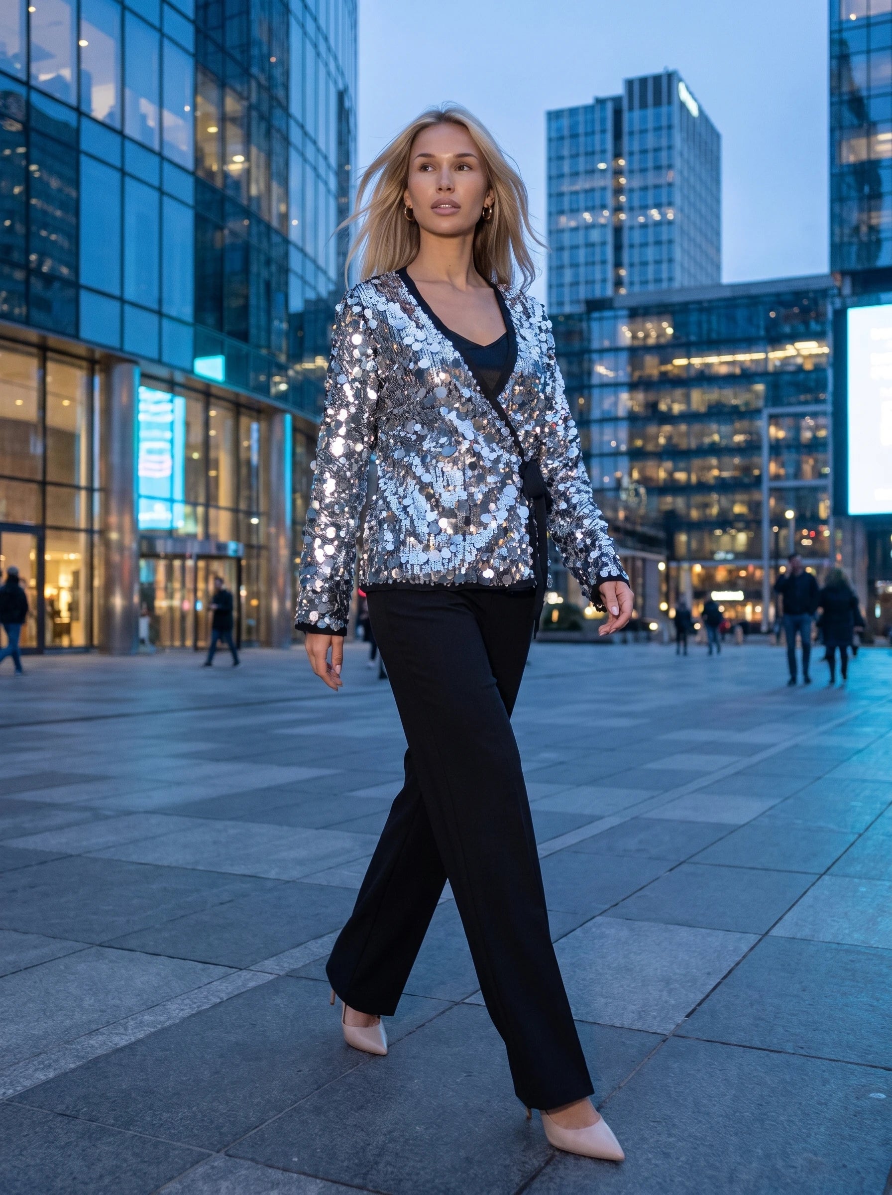 Veste à paillettes argentée Félicie, portée sur une esplanade urbaine à l'heure bleue