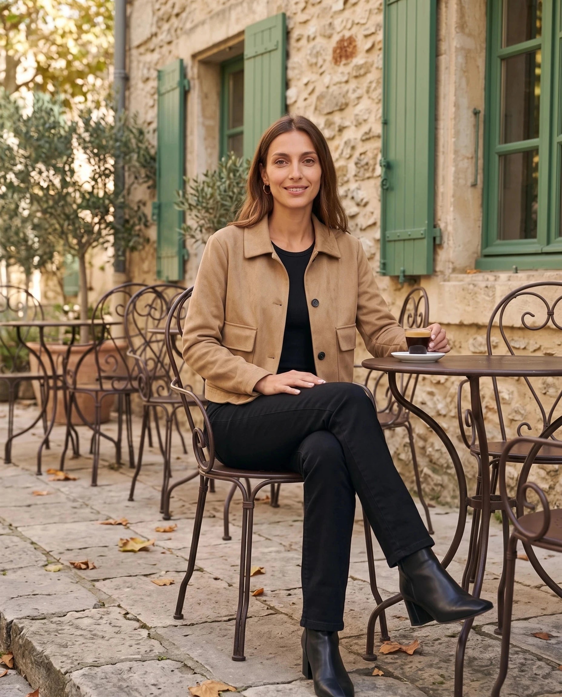 Veste en suédine camel Antonine, portée en terrasse aux volets verts