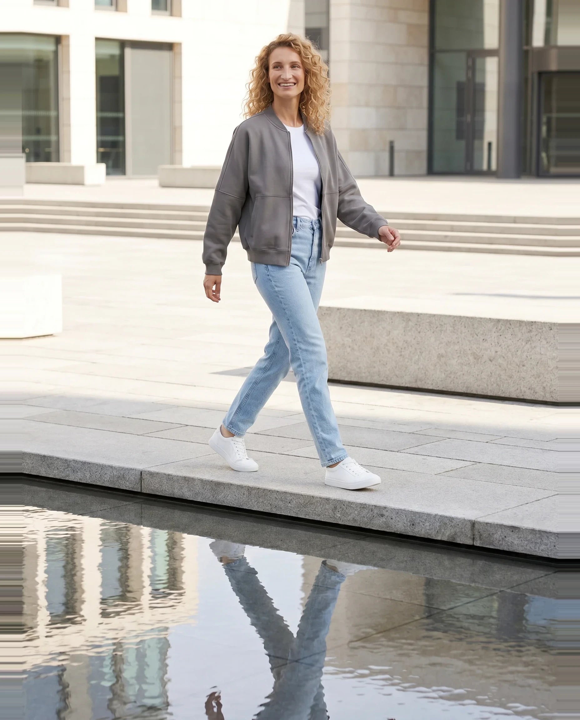 Bomber en molleton gris Denise, porté sur un parvis au miroir d'eau