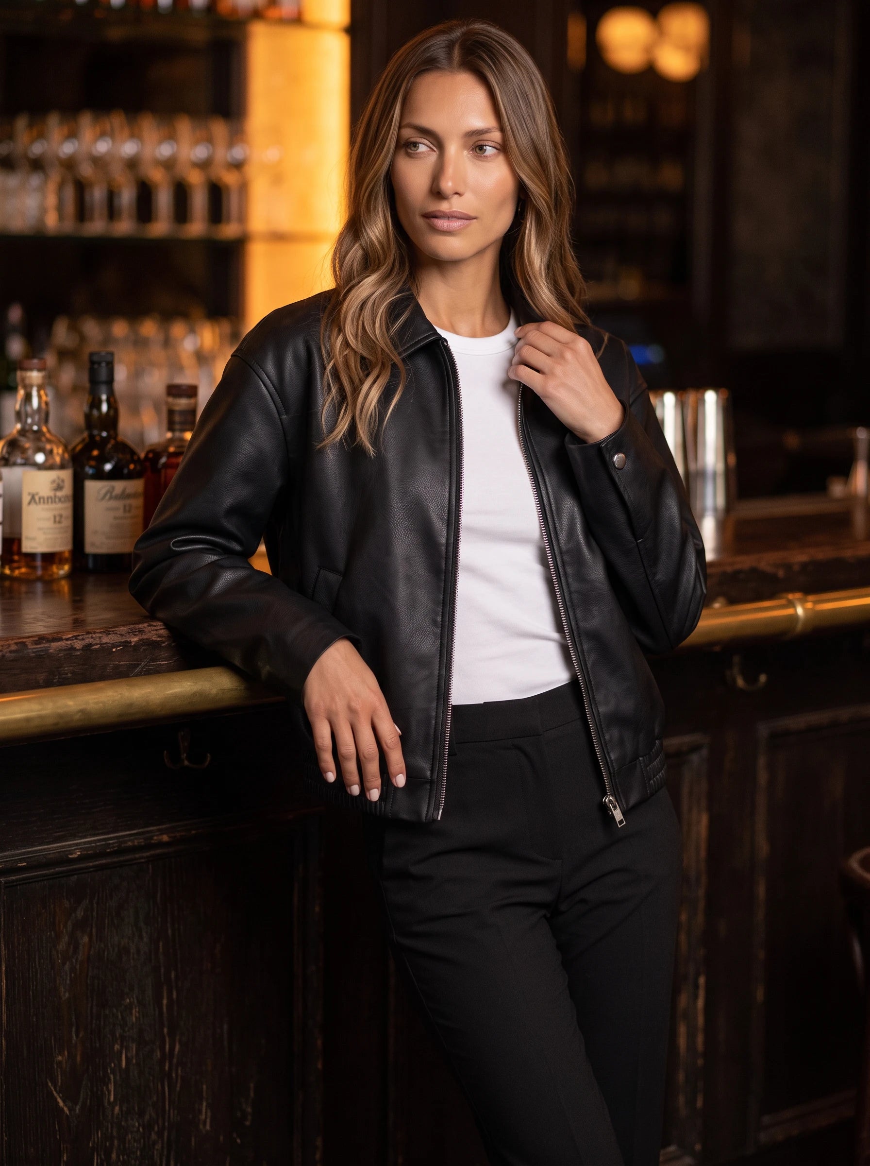 Veste effet cuir noir Louane, portée au comptoir d'un bar feutré
