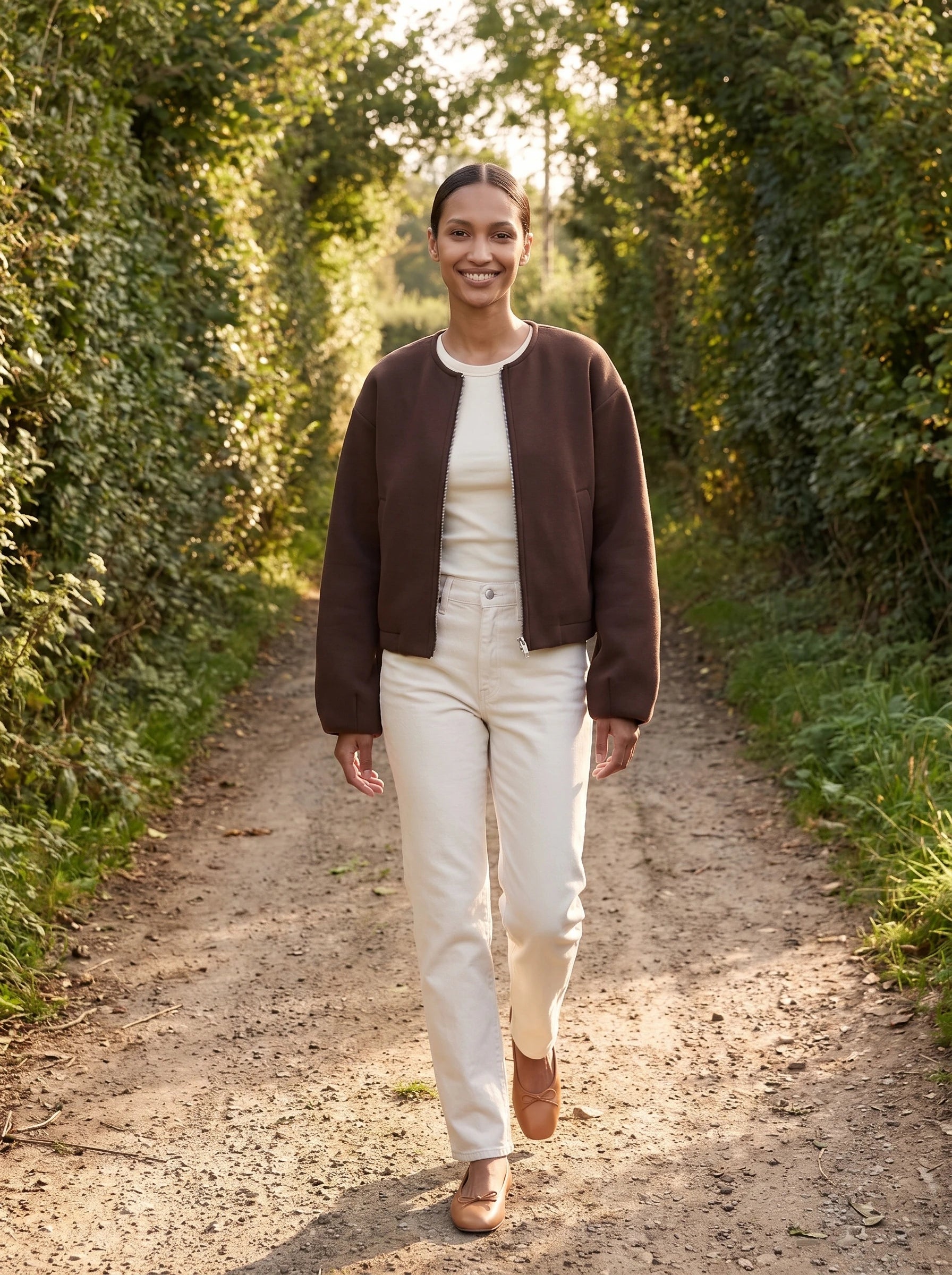 Veste zippée sans col marron Germaine, portée sur un chemin de bocage