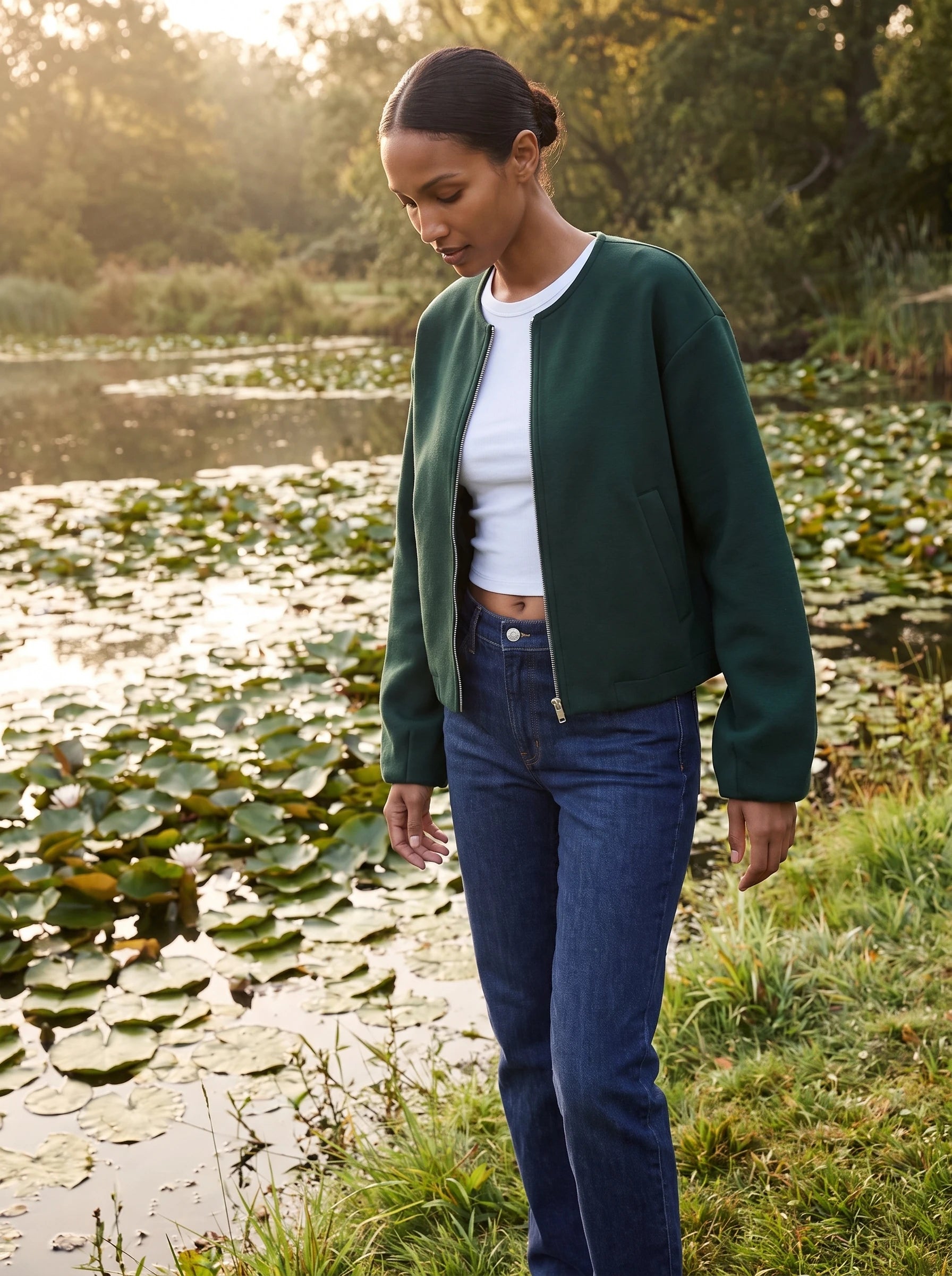 Veste zippée sans col vert bouteille Germaine, portée au bord d'un étang aux nénuphars