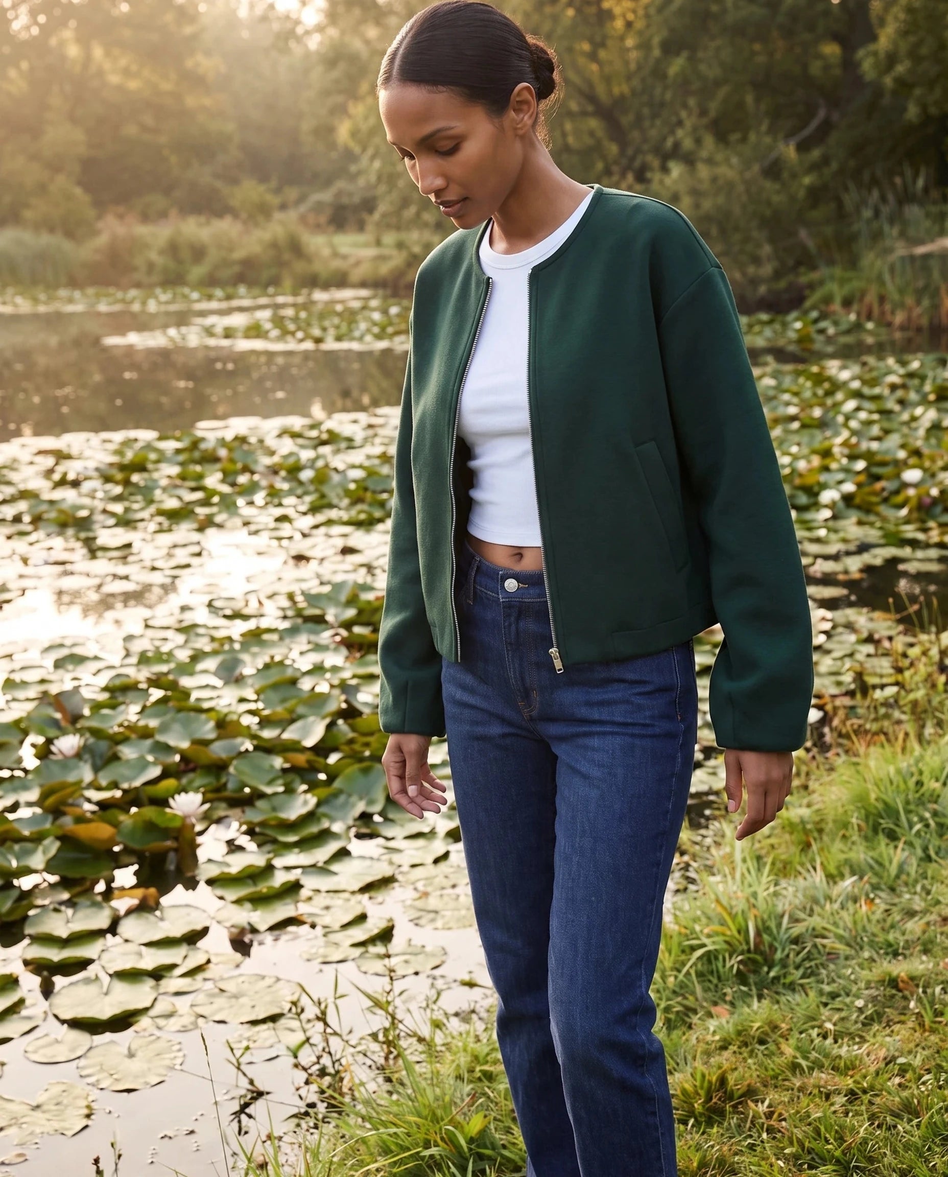 Veste zippée sans col vert bouteille Germaine, portée au bord d'un étang aux nénuphars
